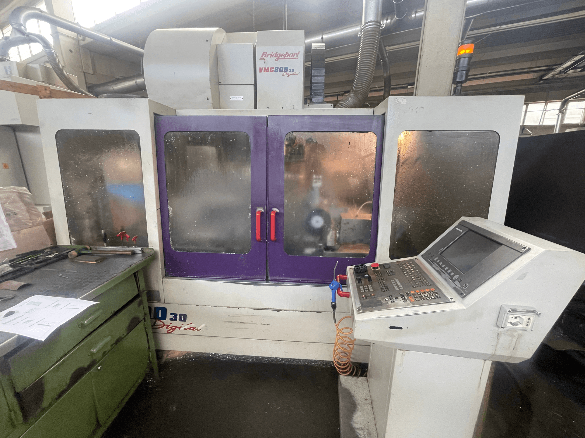 Bridgeport VMC 800/30 Dikey İşleme Merkezi, önden görünüm; kontrol paneli ve mor kapaklar ile yan yüzeydeki aletler gösterilmektedir.