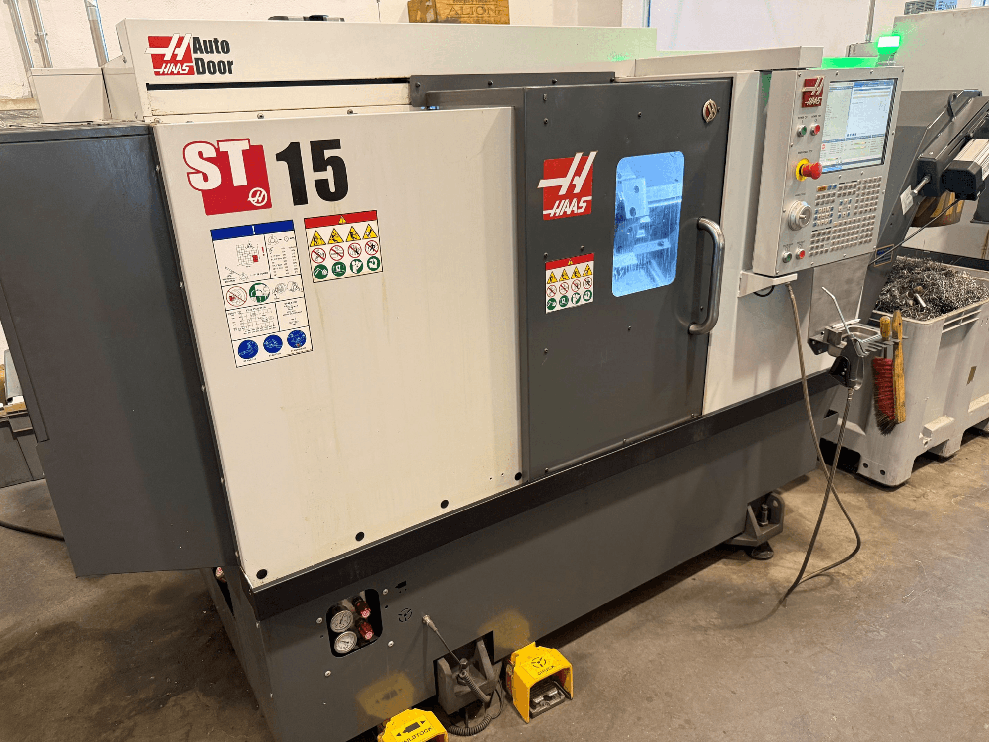 HAAS ST 15 yatay torna tezgahı; kontrol paneli, otomatik kapı ve görünür teknik göstergeleri gösteren önden görünüm.