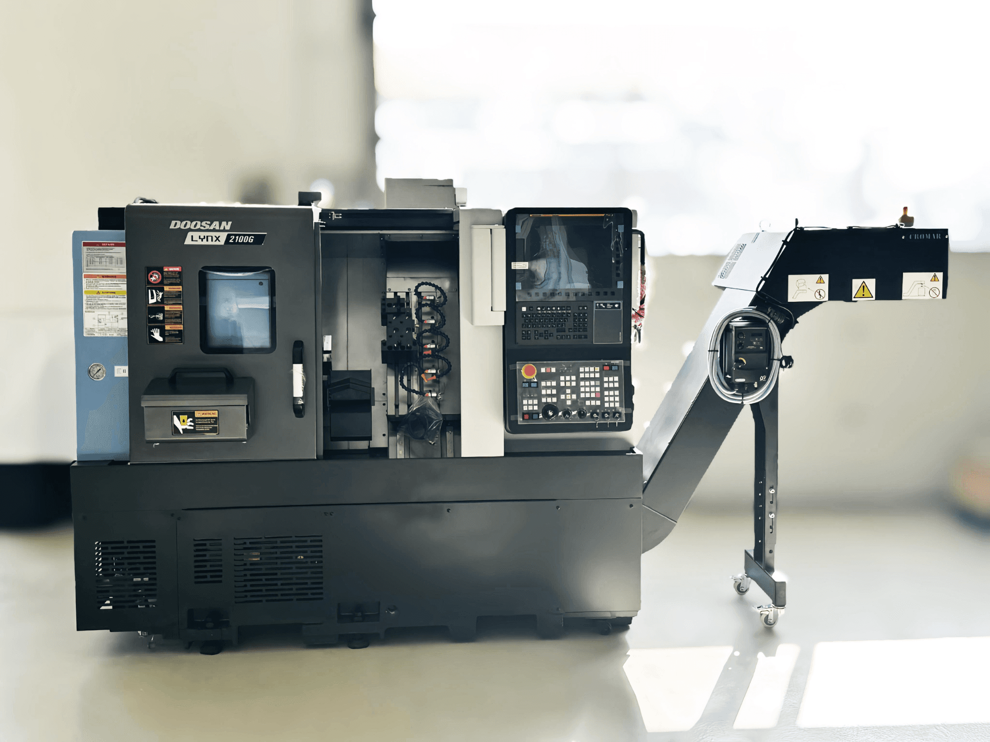 DOOSAN LYNX 2100GA İsviçre tipi torna makinesi, kontrol paneli ve takım tutucu görünür şekilde yandan görünümde.
