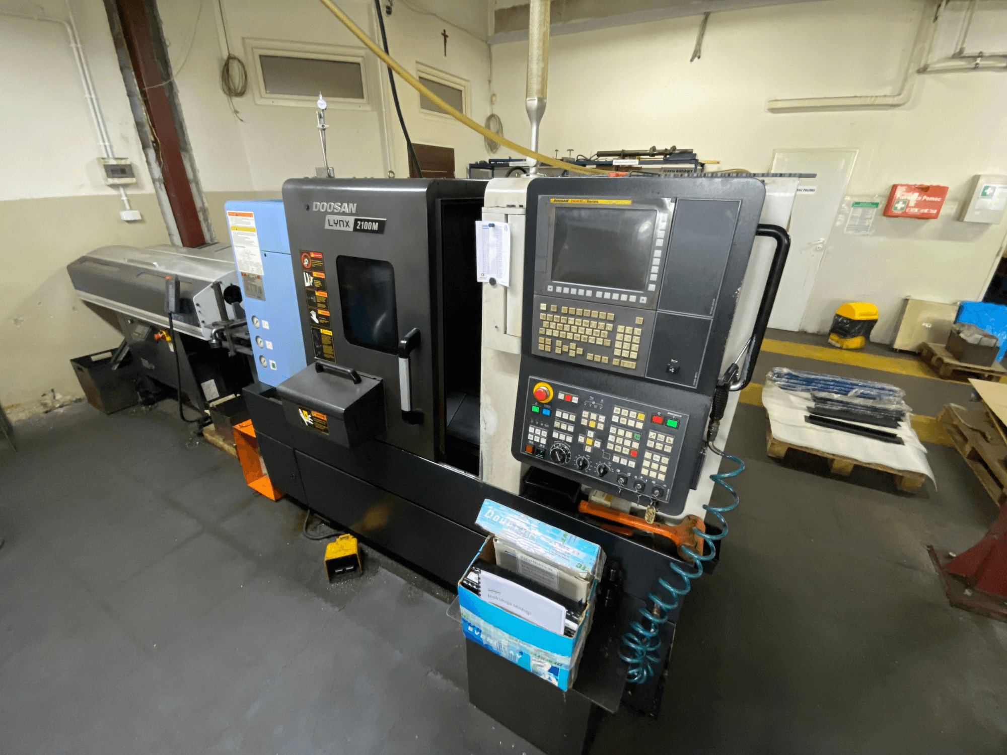 Yan taraftan görülen DOOSAN LYNX 2100MA yatay torna tezgahı; kontrol paneli, takımlar ve işleme alanını göstermektedir.