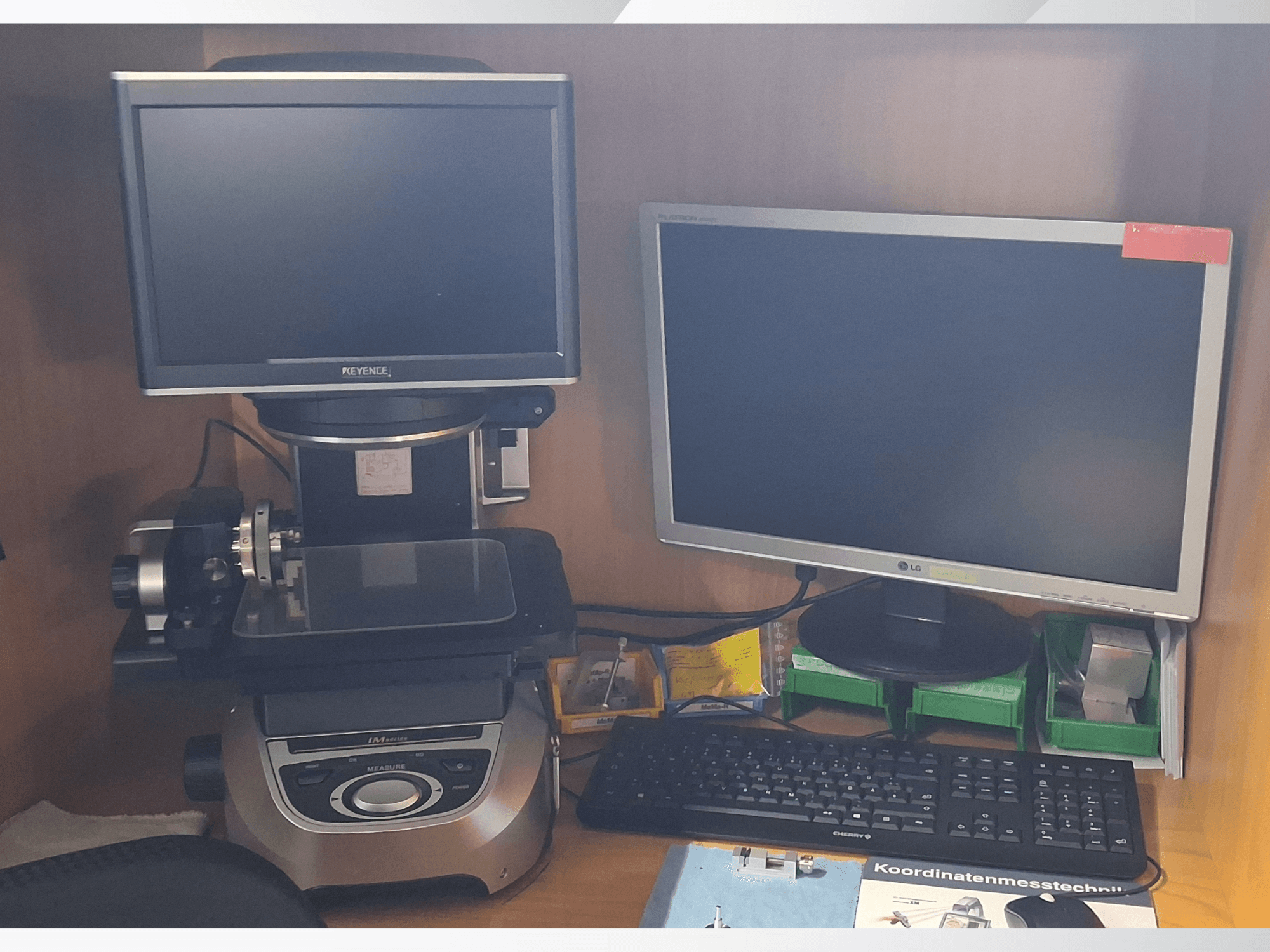 İki monitör (bir LG, bir Keyence) ve bir klavye ile Keyence ölçüm sistemi, önden görünüm.