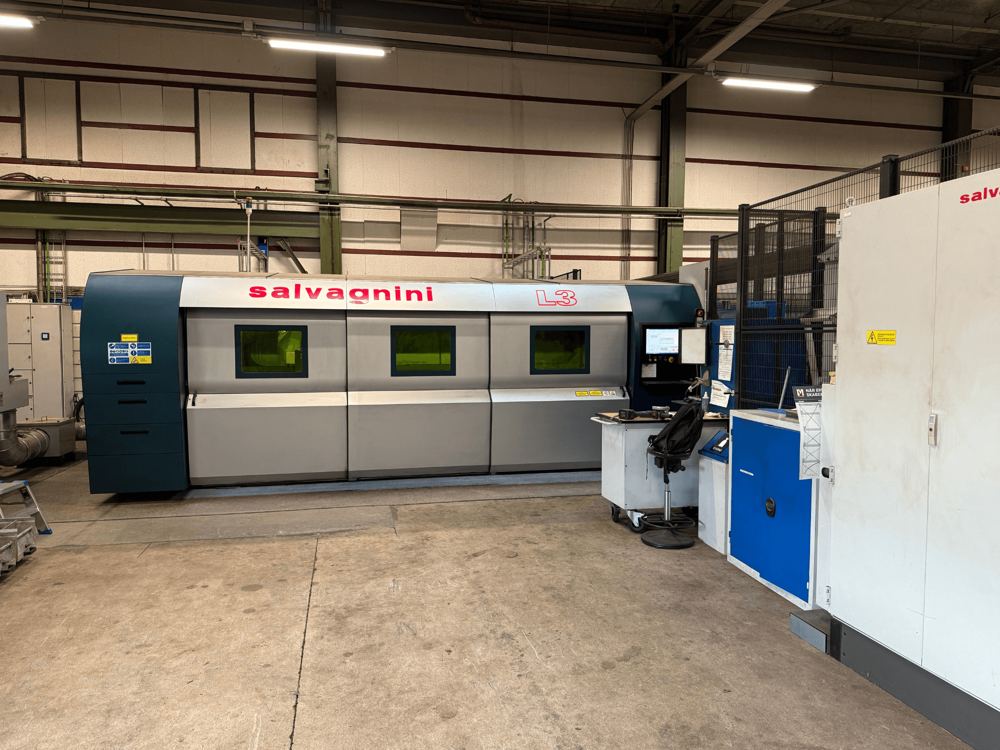 Fabrika ayarlarında Salvagnini L3-4020 fiber lazer kesim makinesi, önden görünüm; kontrol paneli ve taşıma sistemi ile birlikte.