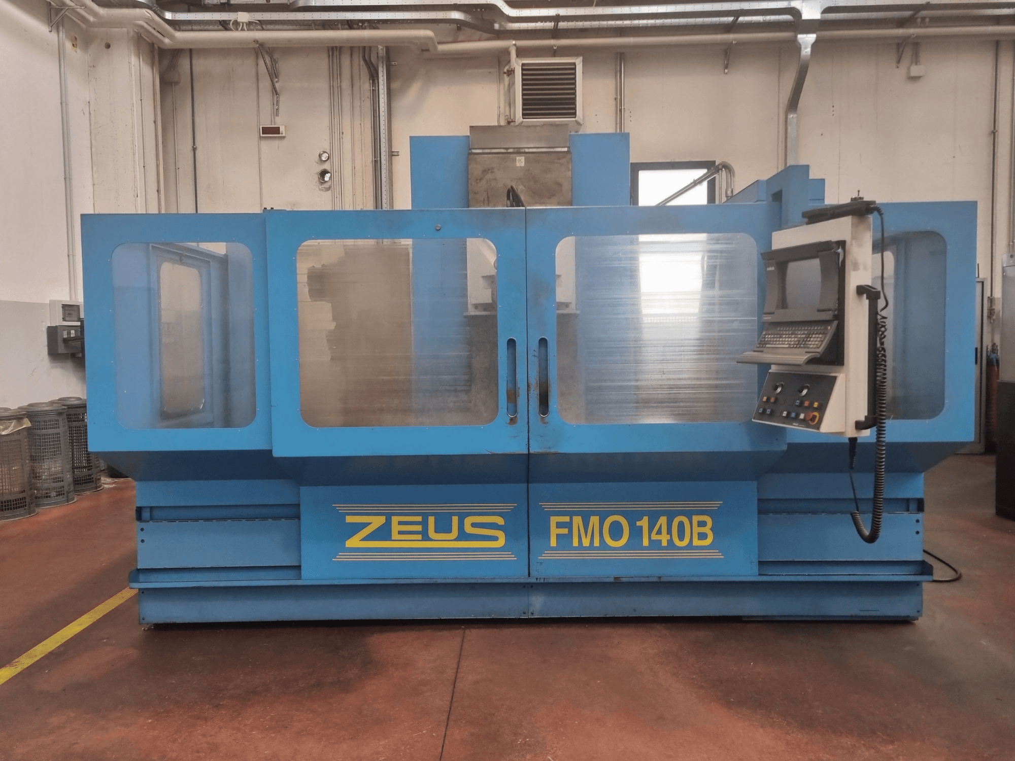 Zeus FMO 140B makine mavi, önden görünüm; kontrol paneli ve görünürlük için büyük şeffaf paneller içerir.
