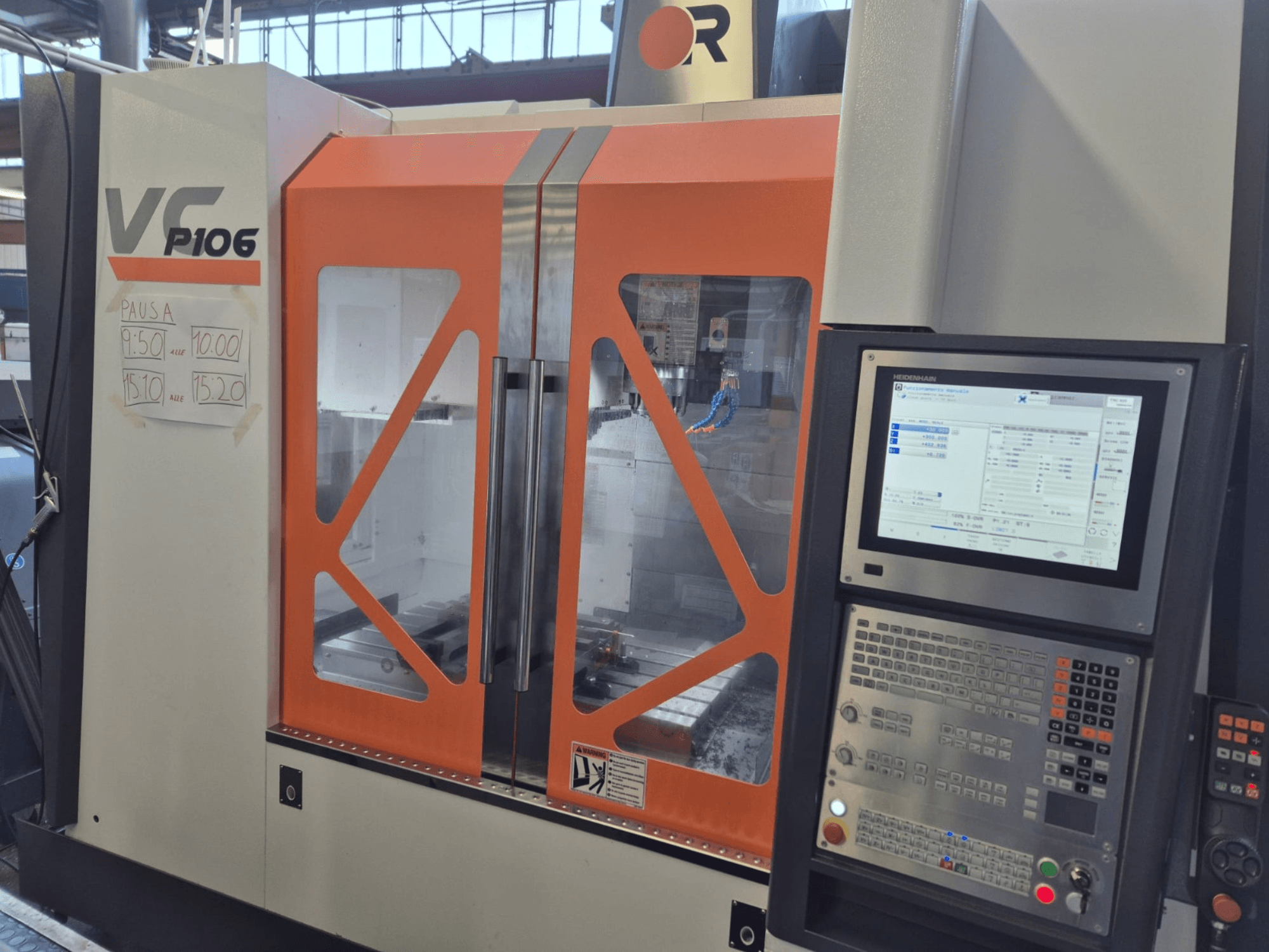 Alt metin: Turuncu ve gri VF P106 CNC makinesi, önden görünüm, kağıt üzerinde bir kontrol paneli ve programlanmış çalışma süreleri görüntüleniyor.