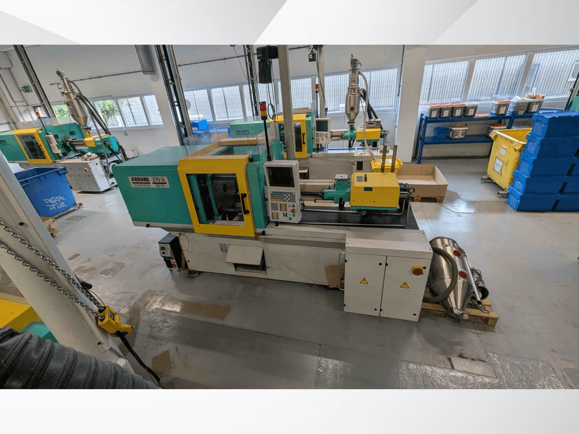 Bir atölyede, kontrol paneli ve makine bileşenleriyle birlikte Arburg 370 U 500-170 dikey enjeksiyon kalıplama makinesinin önden görünümü.