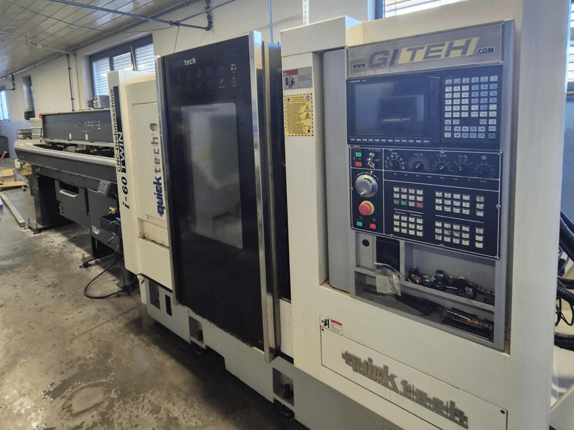 Quick Tech i-60 ikiz CNC makinesi, önden görünüm, GITEH kontrol paneli ve çalışma düğmeleri, bir atölye ortamında.