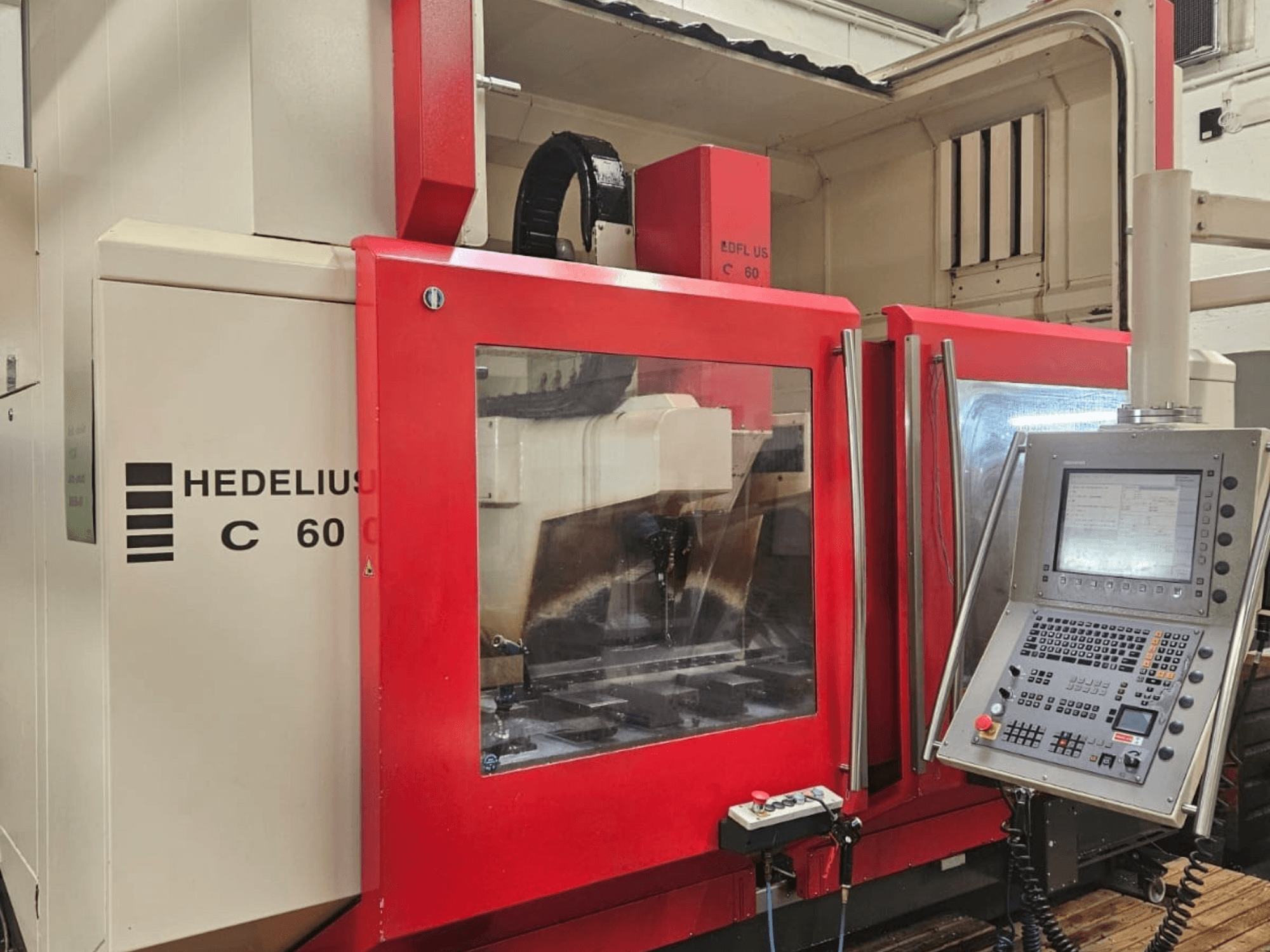 HEDELIUS C60 dikey işleme merkezi yandan, kırmızı ön panel ve ekranlı kontrol konsoluna sahiptir.
