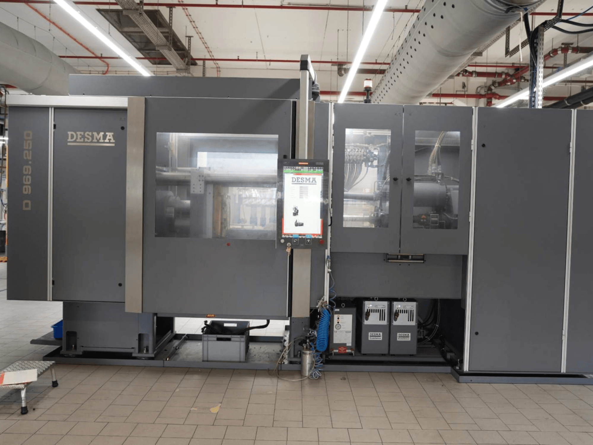 Kloeckner Desma D 969.250 Z (S3) dikey enjeksiyon kalıplama makinesi, fabrika ortamında, kontrol paneli ile birlikte önden görünüm.