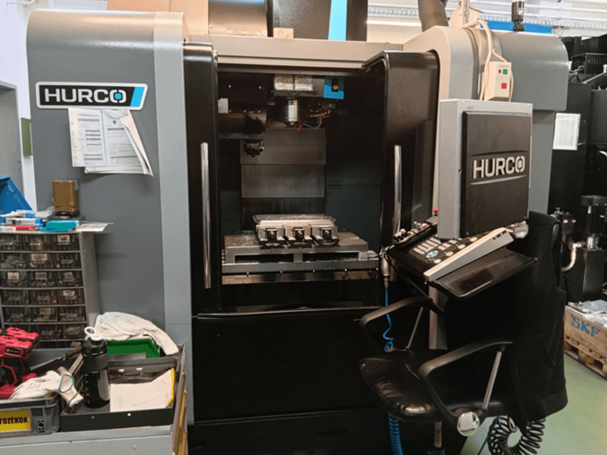 Hurco VMX 30i Dikey İşleme Merkezinin önden görünümü, kontrol paneli, çalışma tezgahı ve operasyonel kurulum.