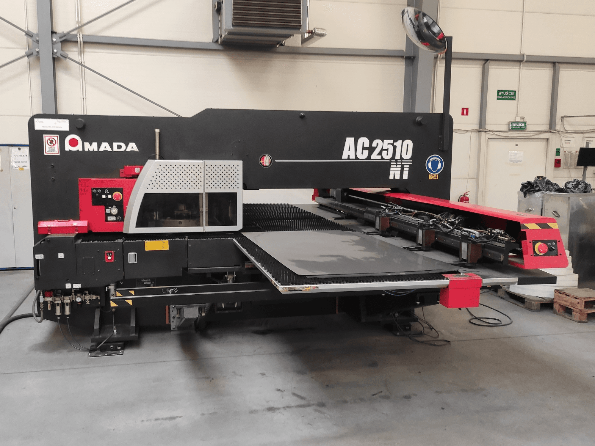 Amada AC2510 NT CNC delme makinesi, önden görünüm, kontrol paneli ve sac yükleme alanı.