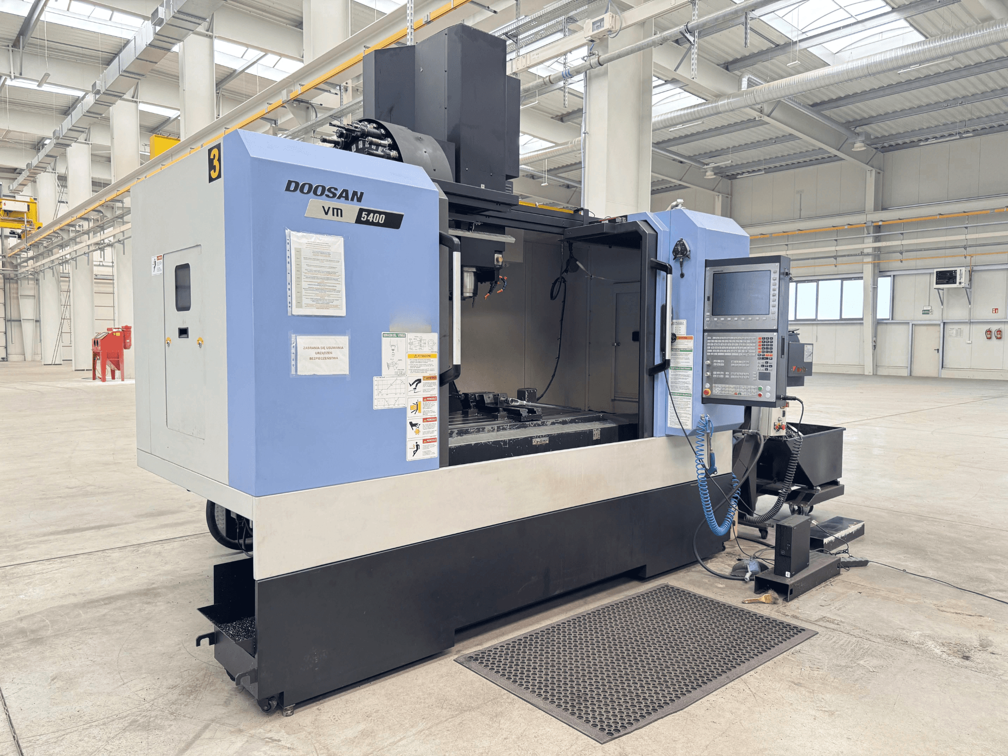 DOOSAN VM 5400 Dik İşleme Merkezi, geniş endüstriyel ortamda kontrol panelini ve çalışma alanını gösteren önden görünüm.