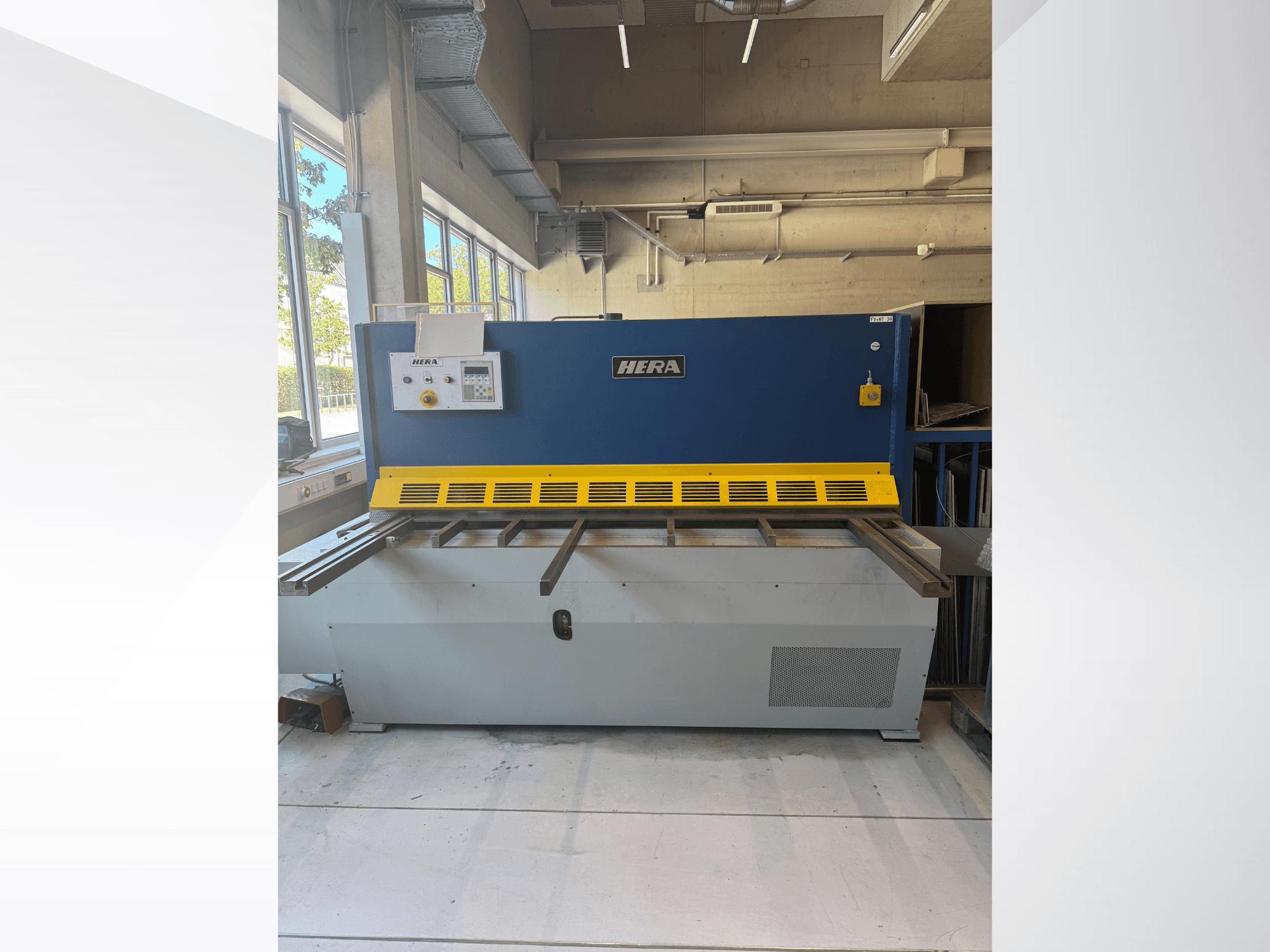 HERA TS 2000x6 hidrolik kesme makinesinin önden görünümü; mavi ve sarı renkli tasarımı, kontrol paneli ve kesme yatağı ile birlikte.