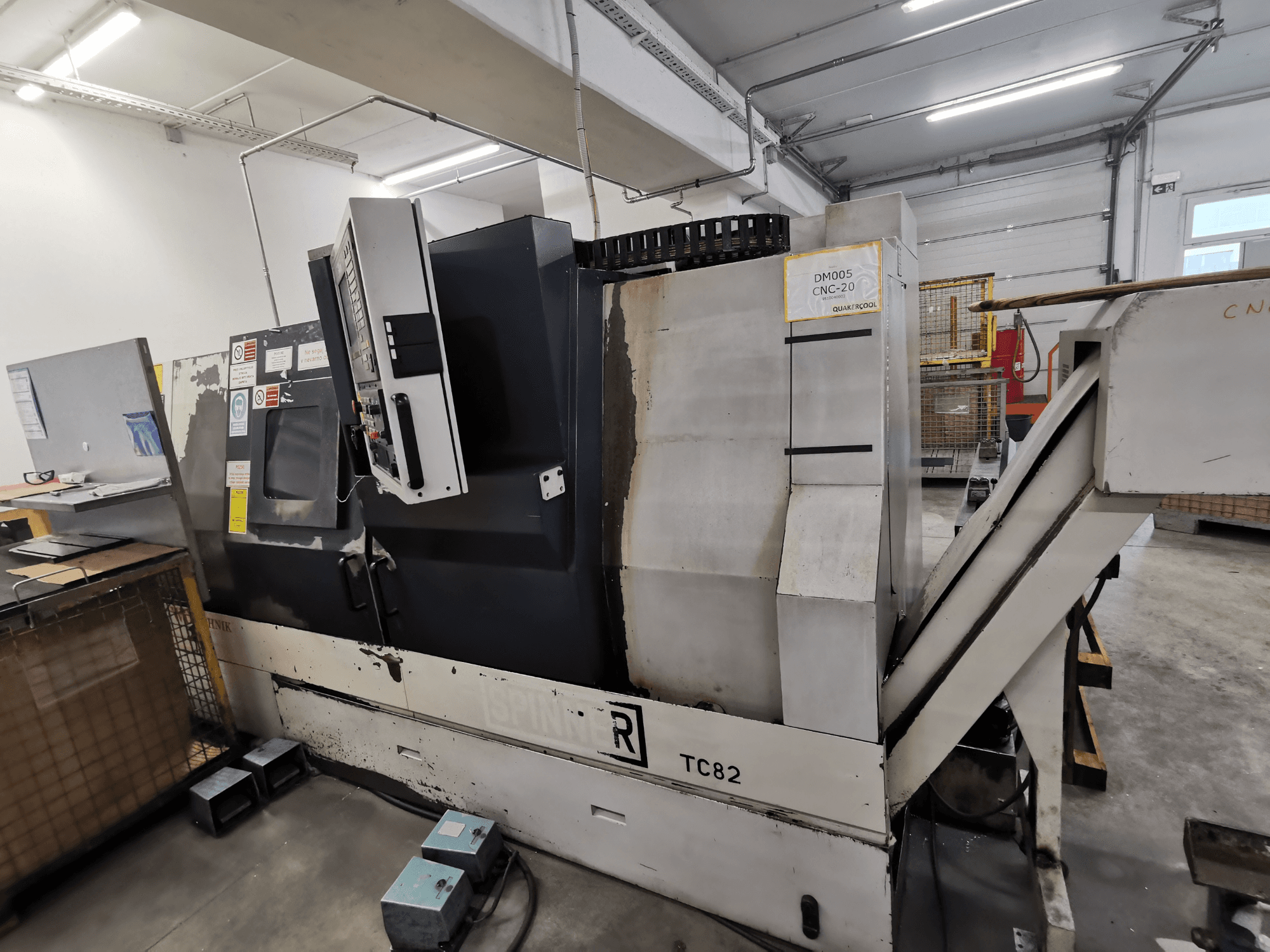 CNC makinesi, marka Spinner, model TC82, atölye ortamında kontrol panelini ve hurda çıkarma oluğunu gösteren yandan görünüm.