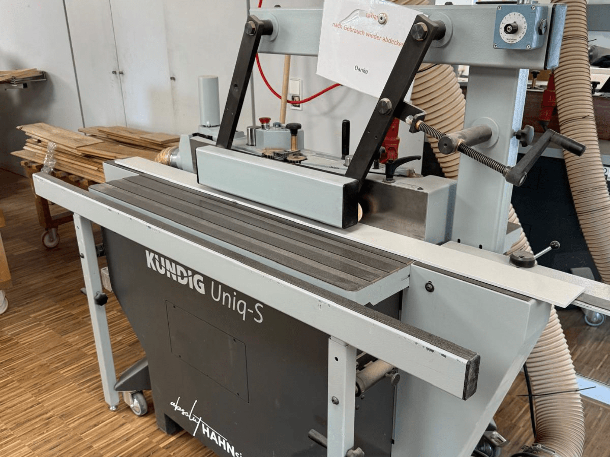 Atölyede Kundig UNIQ-S bant zımpara makinesi, zımpara bandını ve ayarlanabilir destek kollarını gösteren yandan görünüm.