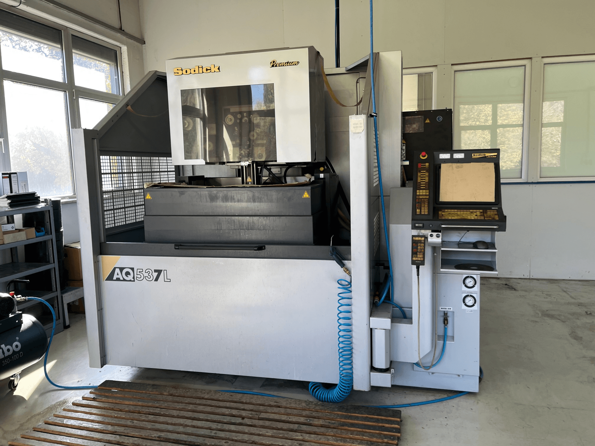 Sodick AQ537L elektrik deşarj makinesinin (EDM) önden görünümü, kontrol paneli, su soğutma hatları ve çalışma alanı.