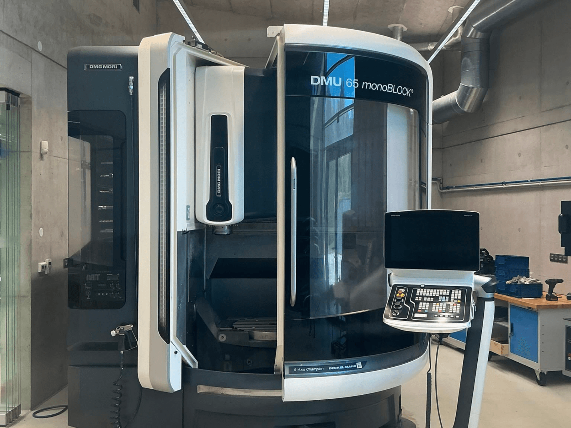 DMG MORI DMU 65 monoBLOCK dikey işleme merkezi, önden görünüm; atölye ortamında kontrol paneli ve makine detaylarını göstermektedir.