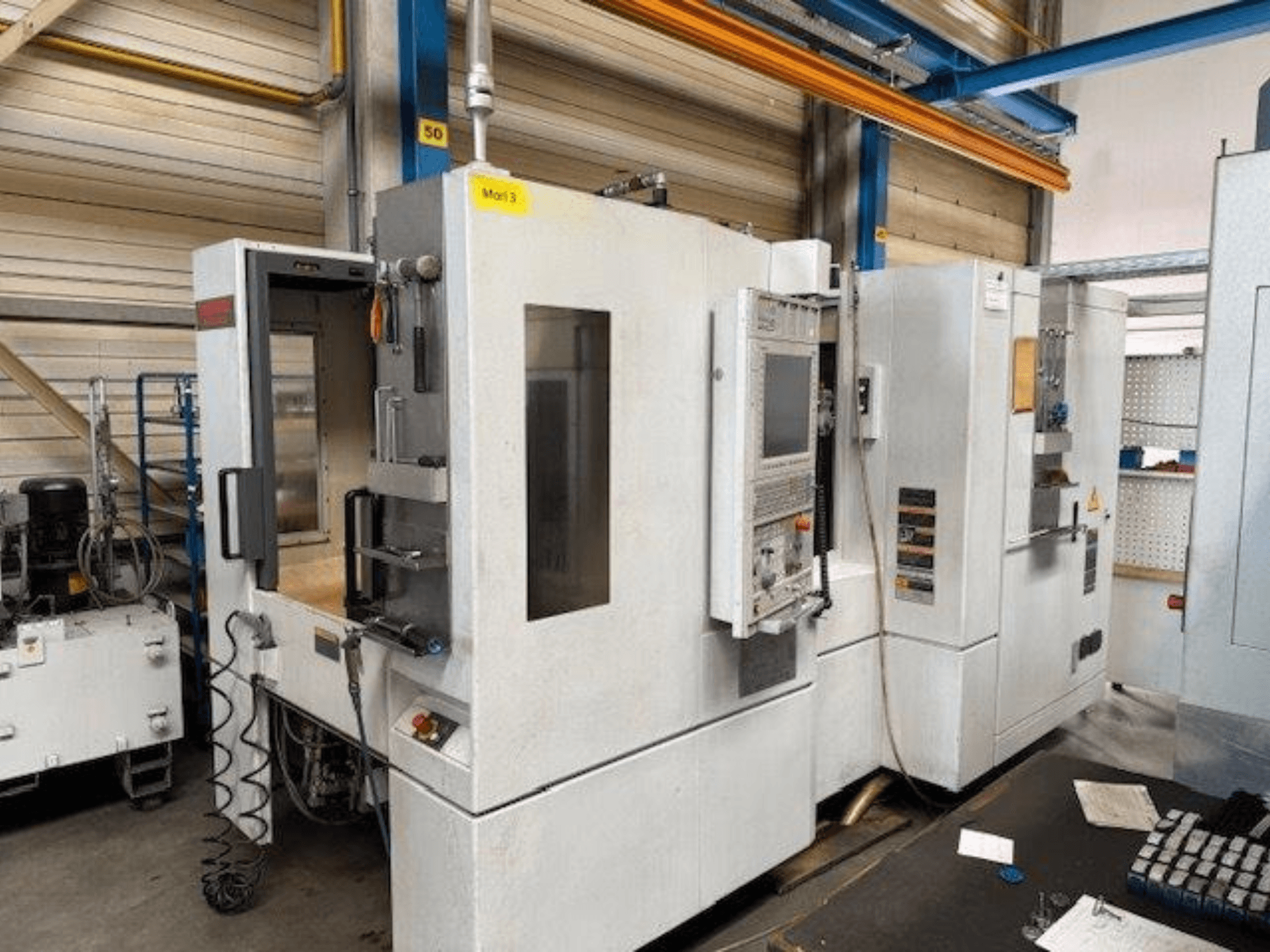 Bir MORI SEIKI NH4000 DCG yatay işleme merkezinin önden görünümü, açık kapı ve kontrol paneli görünür, çalışma alanını gösterir.