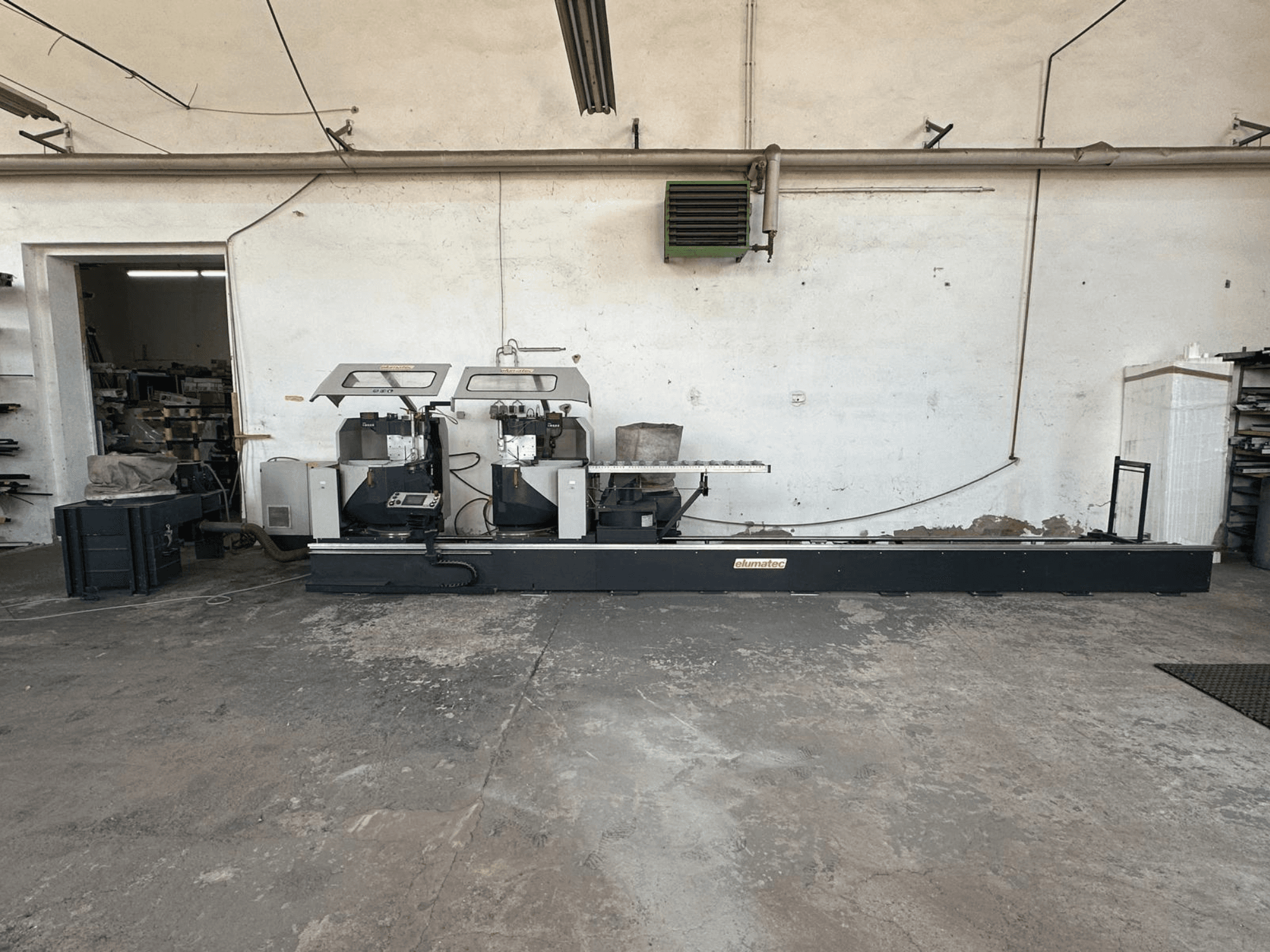 Bir atölyede Elumatec DG 244 daire metal testeresi, sağlam bir taban üzerinde çift testereyi ve çalıştırma kontrollerini gösteren yandan görünüm.