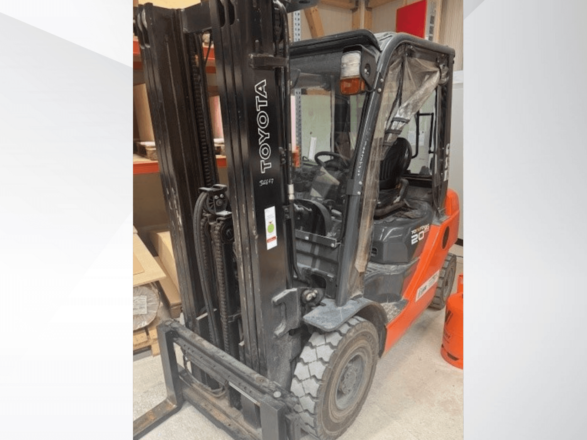 Toyota 20 forklift önden bakıldığında siyah direği, şeffaf kabini ve yanında turuncu propan tankı ile dikkat çekiyor.