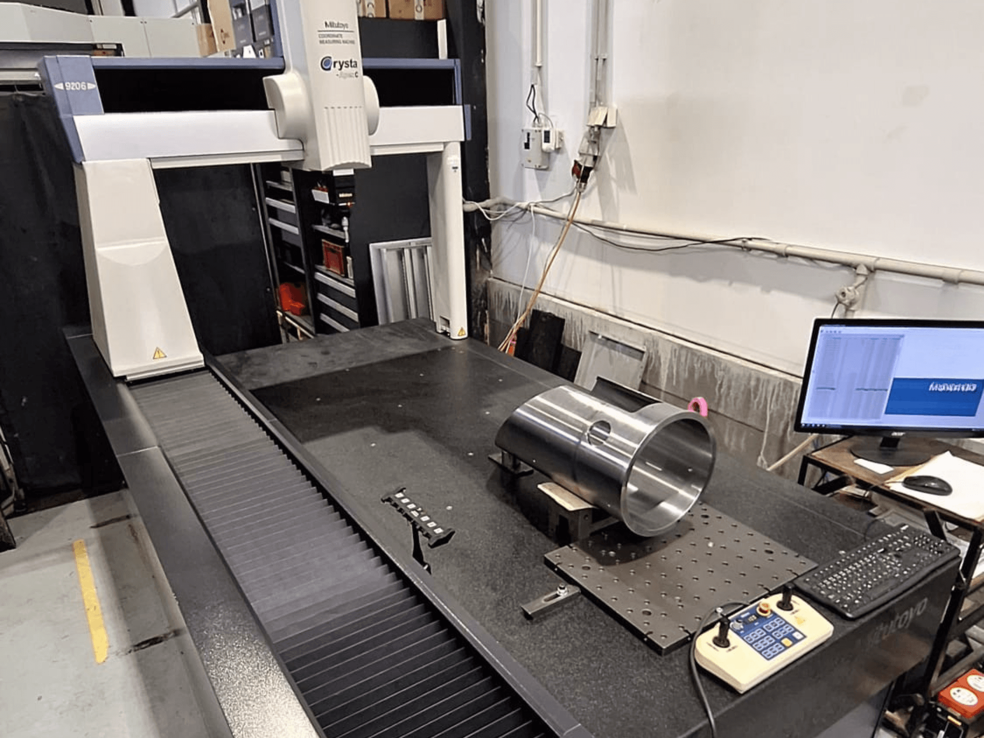 Mitutoyo Crysta-Apex C9206 CMM önden görünümde, siyah granit yüzey plakası üzerinde silindirik bir metal parçayı ölçüyor.