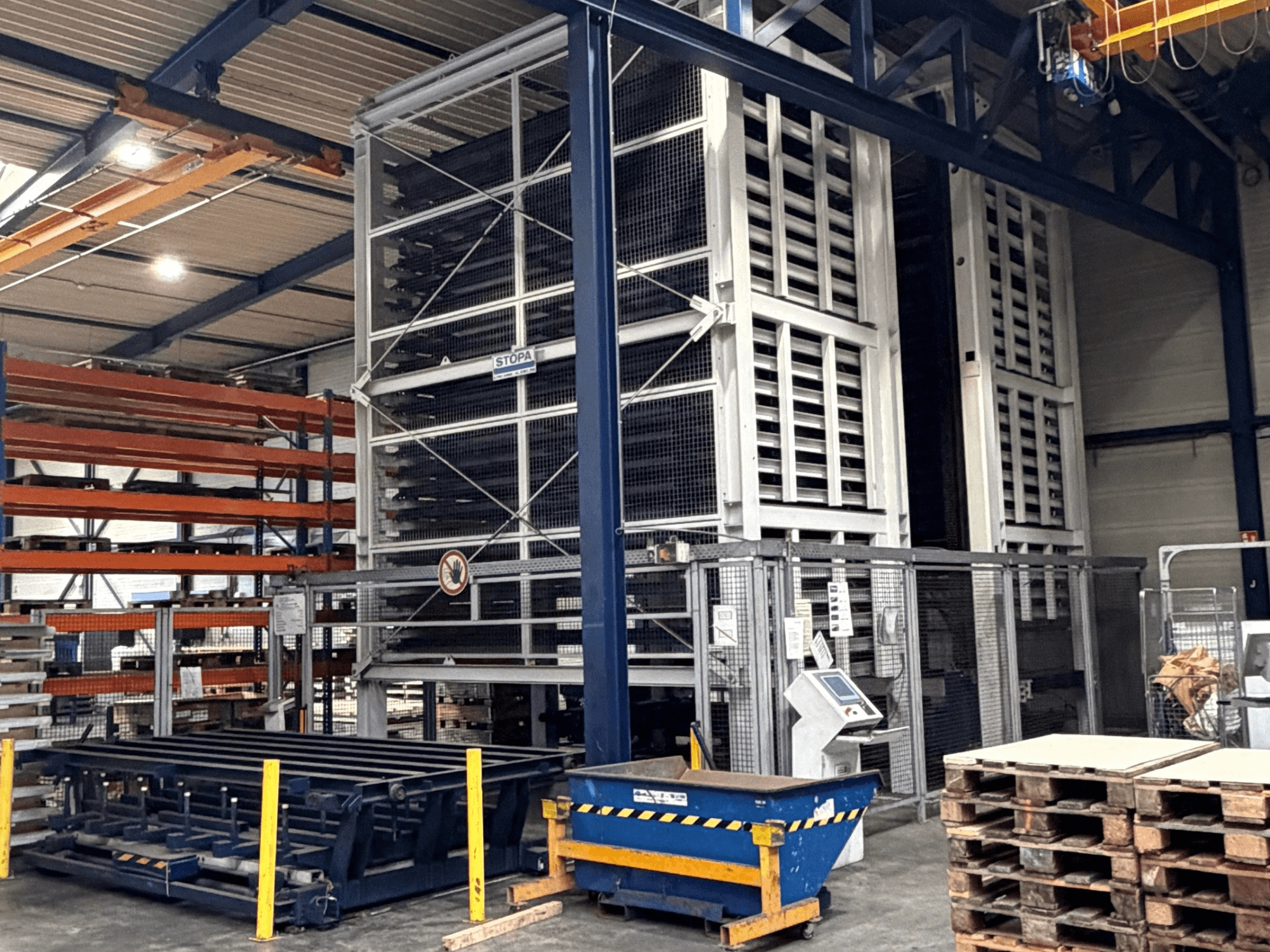 TRUMPF STOPA 4000x2000 otomasyon sistemi bir depoda, depolama alanı içindeki rafları ve kontrol panelini gösteren yandan görünüm.