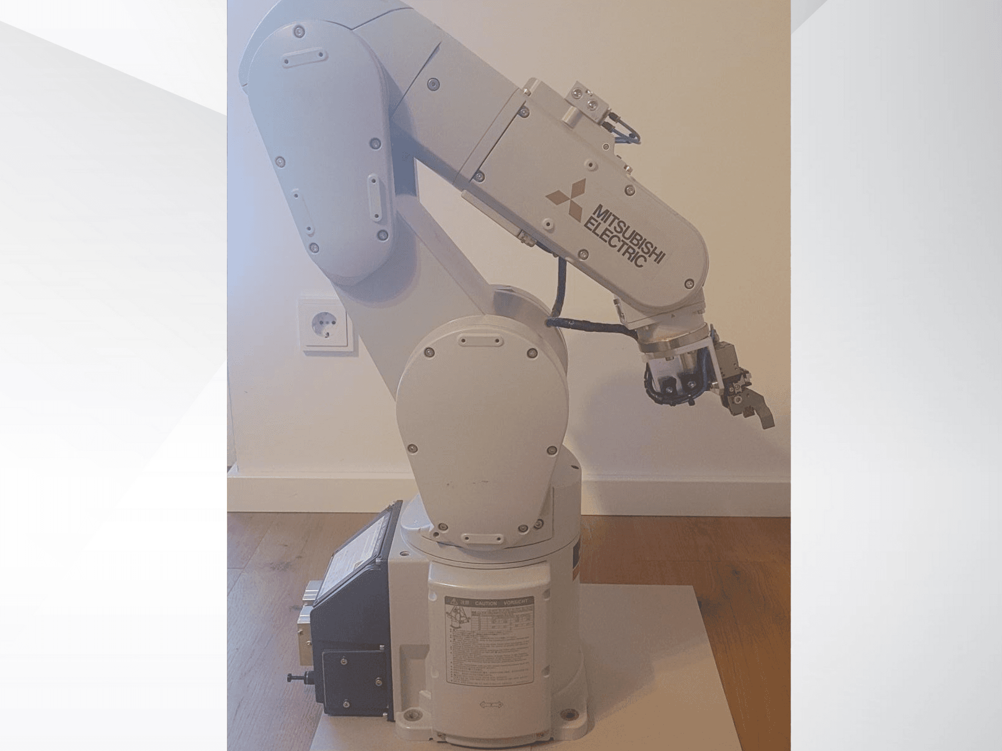 Mitsubishi Electric robot kolu, yandan görünüm, bir kavrayıcı ve çalışma ayarları için tabanda ayrıntılı kontrol paneli içerir.