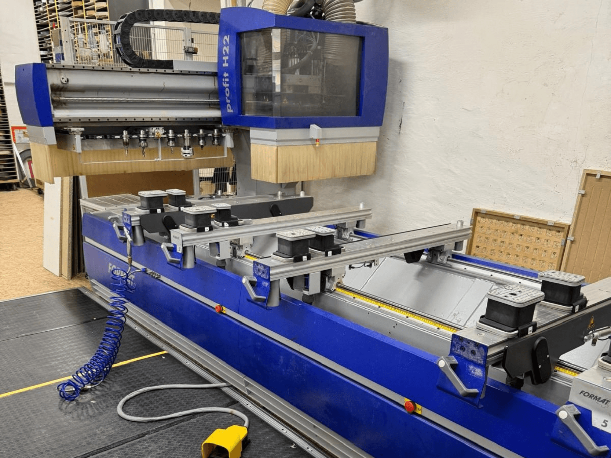 FORMAT4 PROFIT H22 CNC ahşap işleme merkezi, önden görünüm; mavi gövdede işleme aletleri ve tutma kelepçeleri görülmektedir.