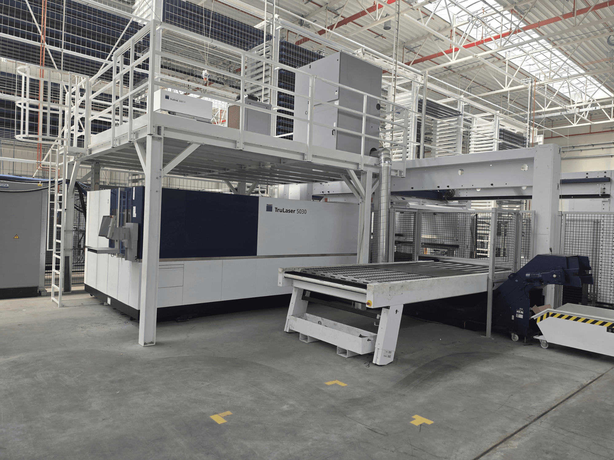 Bir atölyede bulunan TRUMPF TruLaser 5030 fiber L76 FMC makinesi; kesim alanını ve yükleme/boşaltma mekanizmasını gösteren önden görünüm.