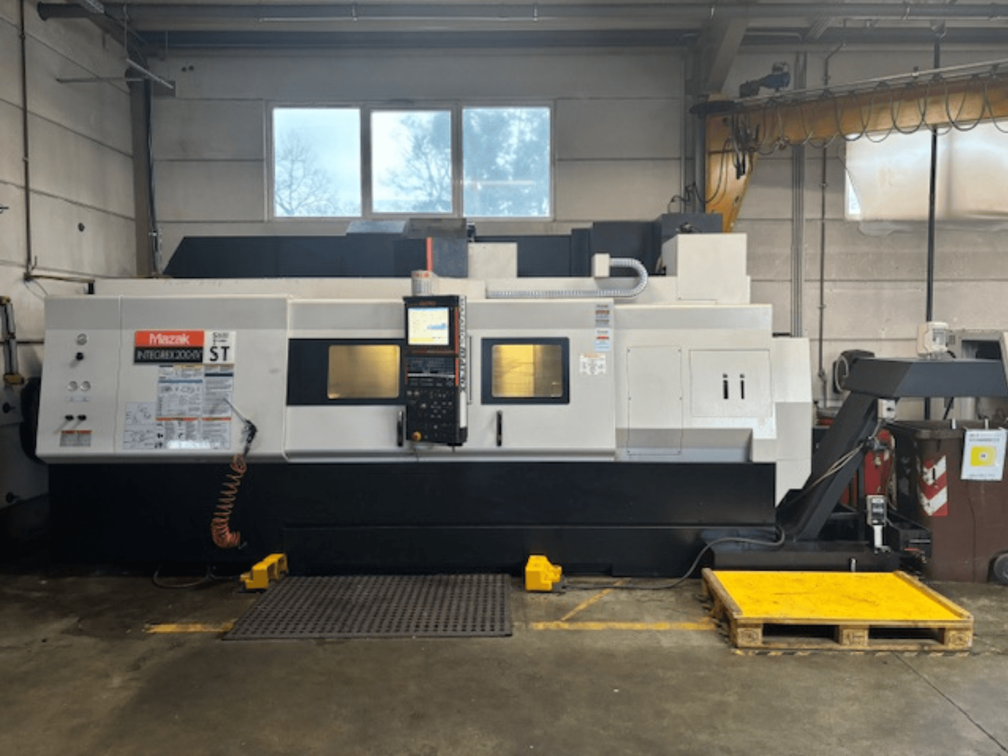 Mazak Integrex 200 SY ST, yandan görünüm, atölye ortamında kontrol panelini, çalışma ekranlarını ve soğutma sıvısı hatlarını gösterir.