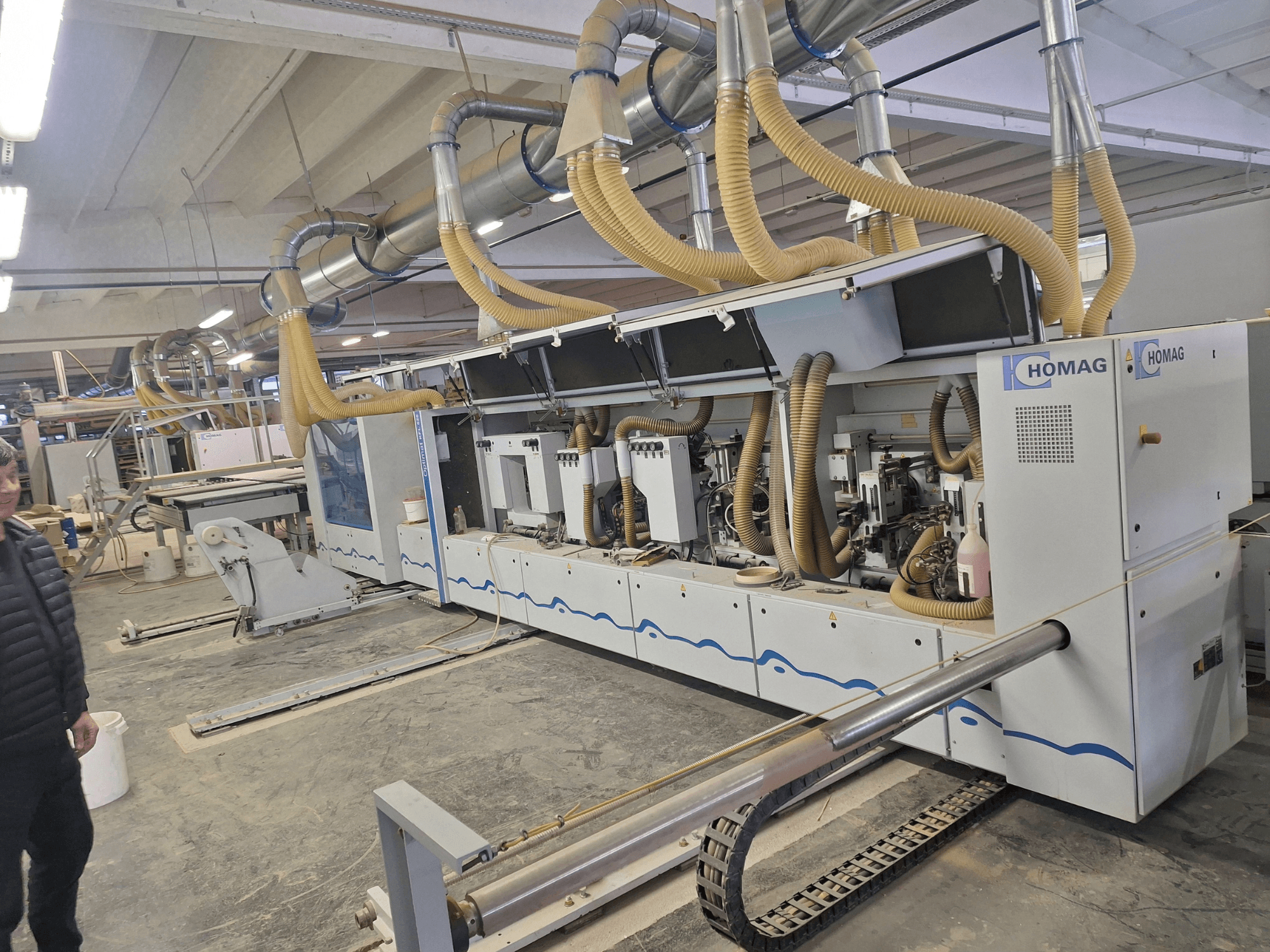 Fabrika ortamında HOMAG ahşap işleme makinesi, çoklu iğleri ve toz emme sistemini gösteren önden görünüm.