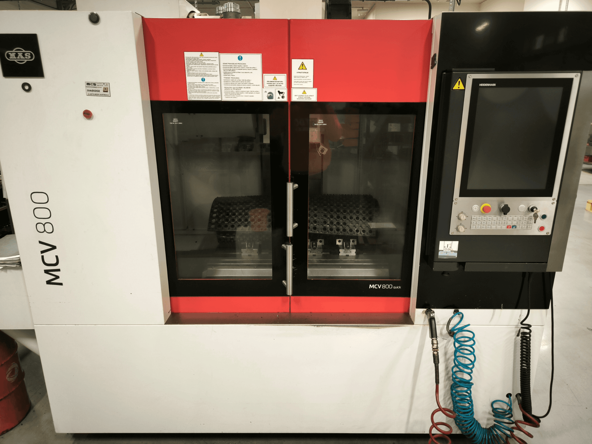 Dikey işleme merkezi KOVOSVIT MAS MCV 800 QUICK, kontrol paneli ve çalışma alanını gösteren çift cam kapılı önden görünüm.
