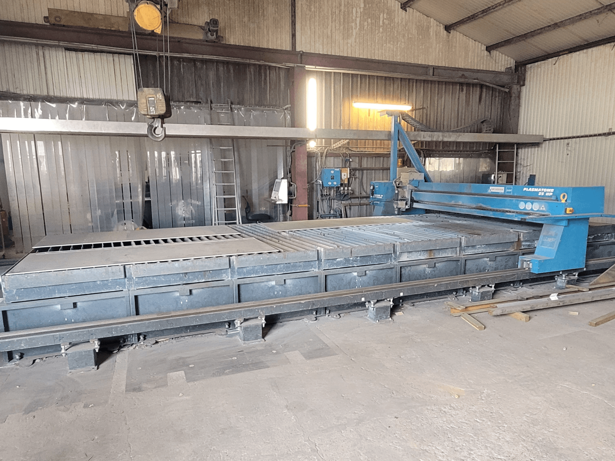 SAF Plasmatone 25Hp plazma kesme makinesi, yandan görünüm, kesme yatağını ve operasyonel bileşenleri endüstriyel bir ortamda sergiliyor.