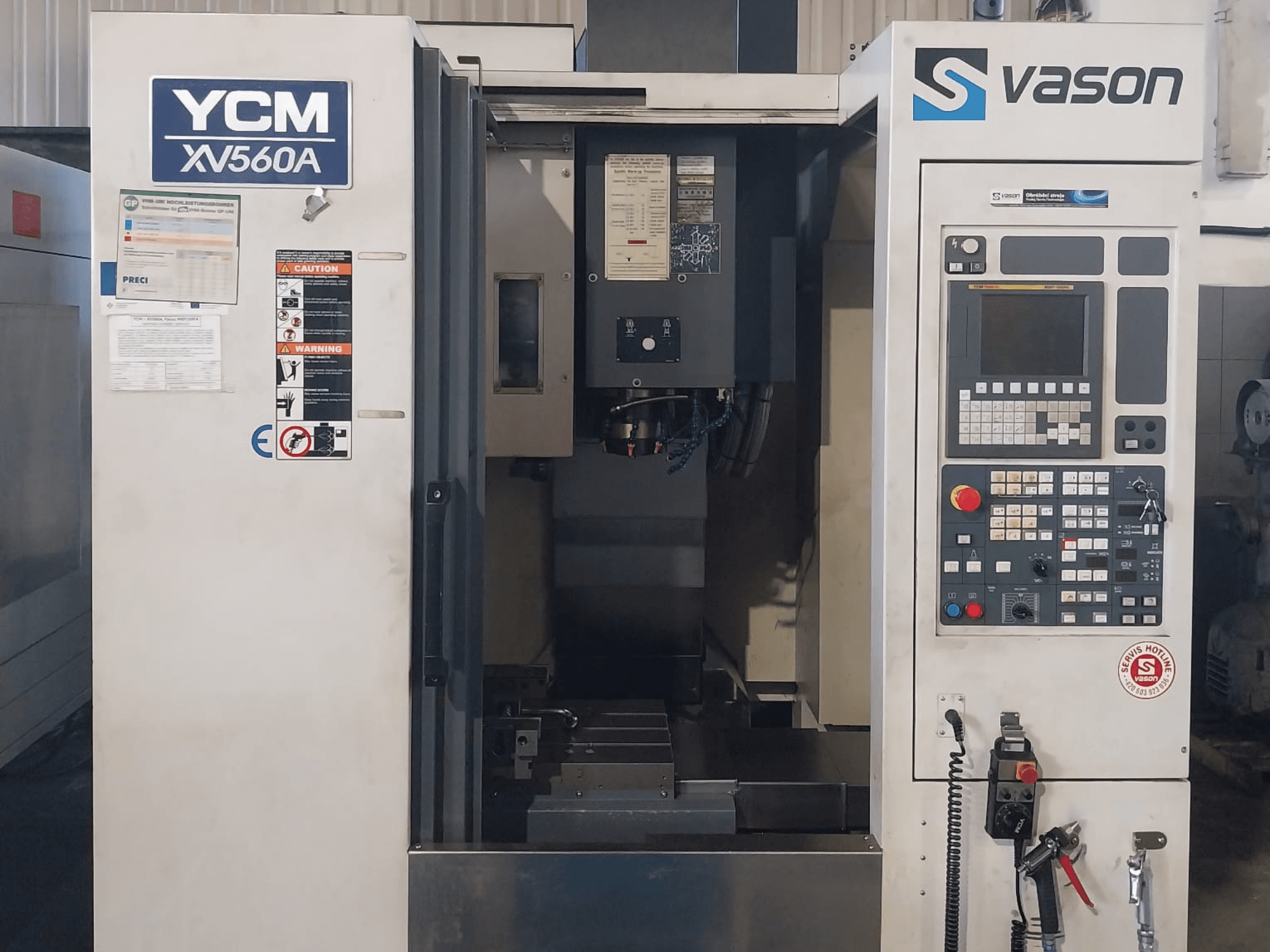 YCM XV 560A Dik İşleme Merkezinin önden görünümü, kontrol paneli ve işleme bileşenlerinin göründüğü çalışma tezgahı.