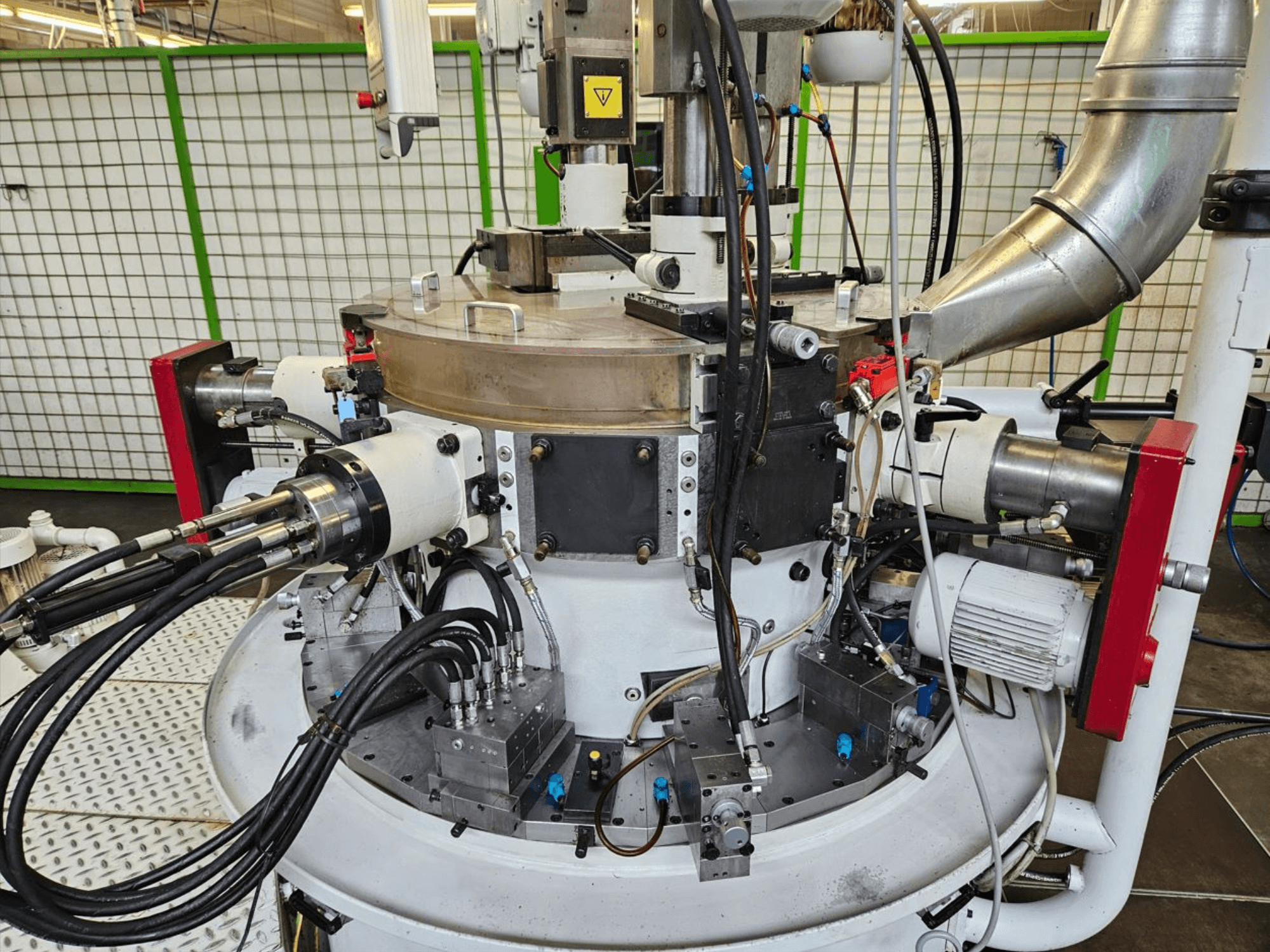 Hidrolik hortumları, metal bileşenleri ve dönen bir tabanı olan endüstriyel bir makinenin yakından görünümü. Marka görünmüyor.