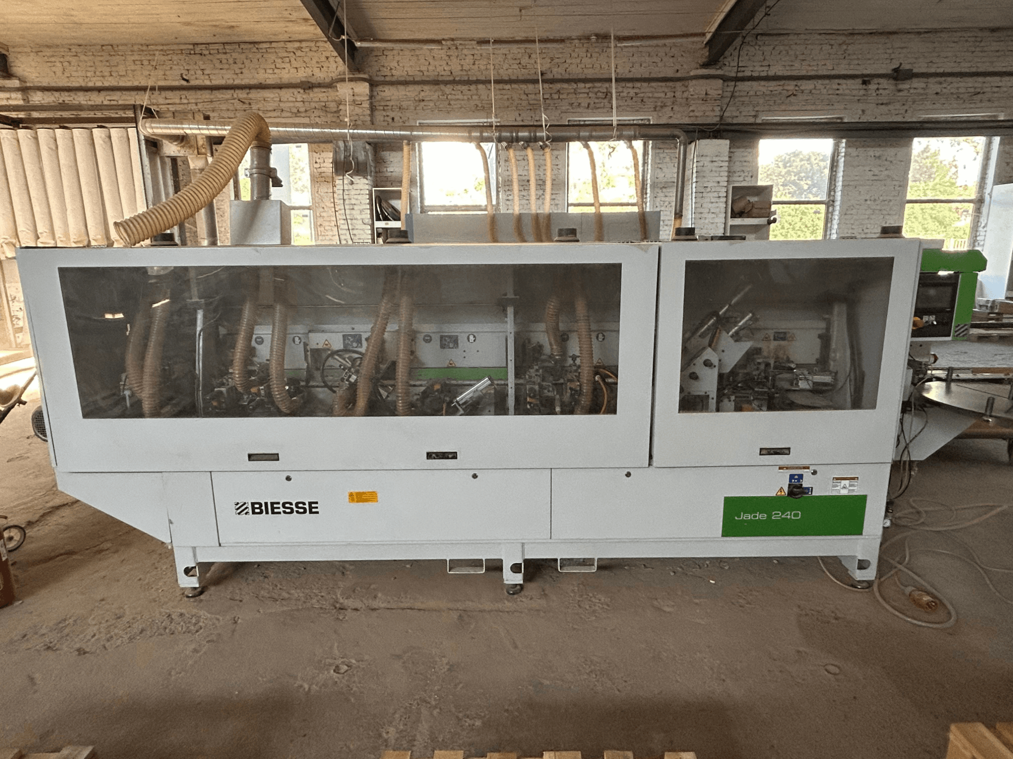 Beyaz ve yeşil renkli BIESSE Jade 240 kenar bantlama makinesi; kontrol paneli ve iç kısımdaki makine detaylarını gösteren önden görünüm.