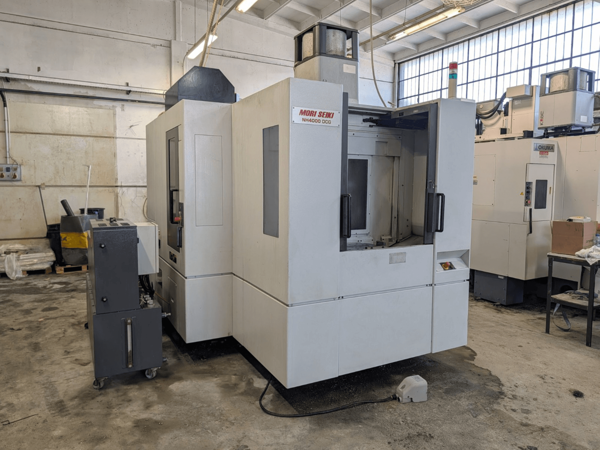 MORI SEIKI NH 4000 DCG yatay işleme merkezi, önden görünüm, kontrol paneli ve çalışma alanı, gri ve beyaz kaplama.