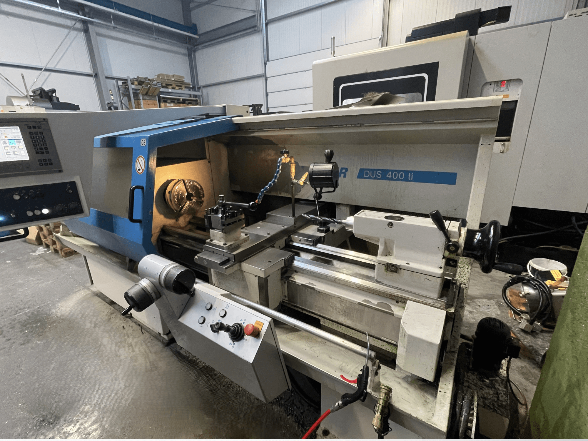 CNC torna makinesi DUS 400 ti'nin önden görünümü, kontrol paneli, takım tutucu ve aydınlatmalı çalışma alanı.