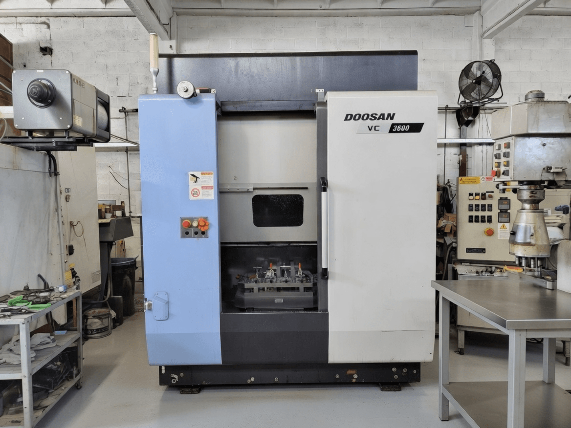 DOOSAN VC 3600 dik işleme merkezinin önden görünümü, kontrol paneli ve çalışma alanını gösteren açık kapı.