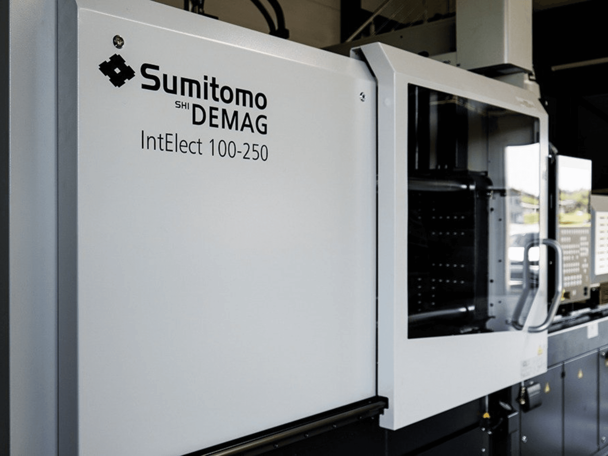 Kontrol paneli ve güvenlik özelliklerine sahip SUMITOMO SHI DEMAG IntElect 100/250 elektrikli enjeksiyon kalıplama makinesinin önden görünümü.