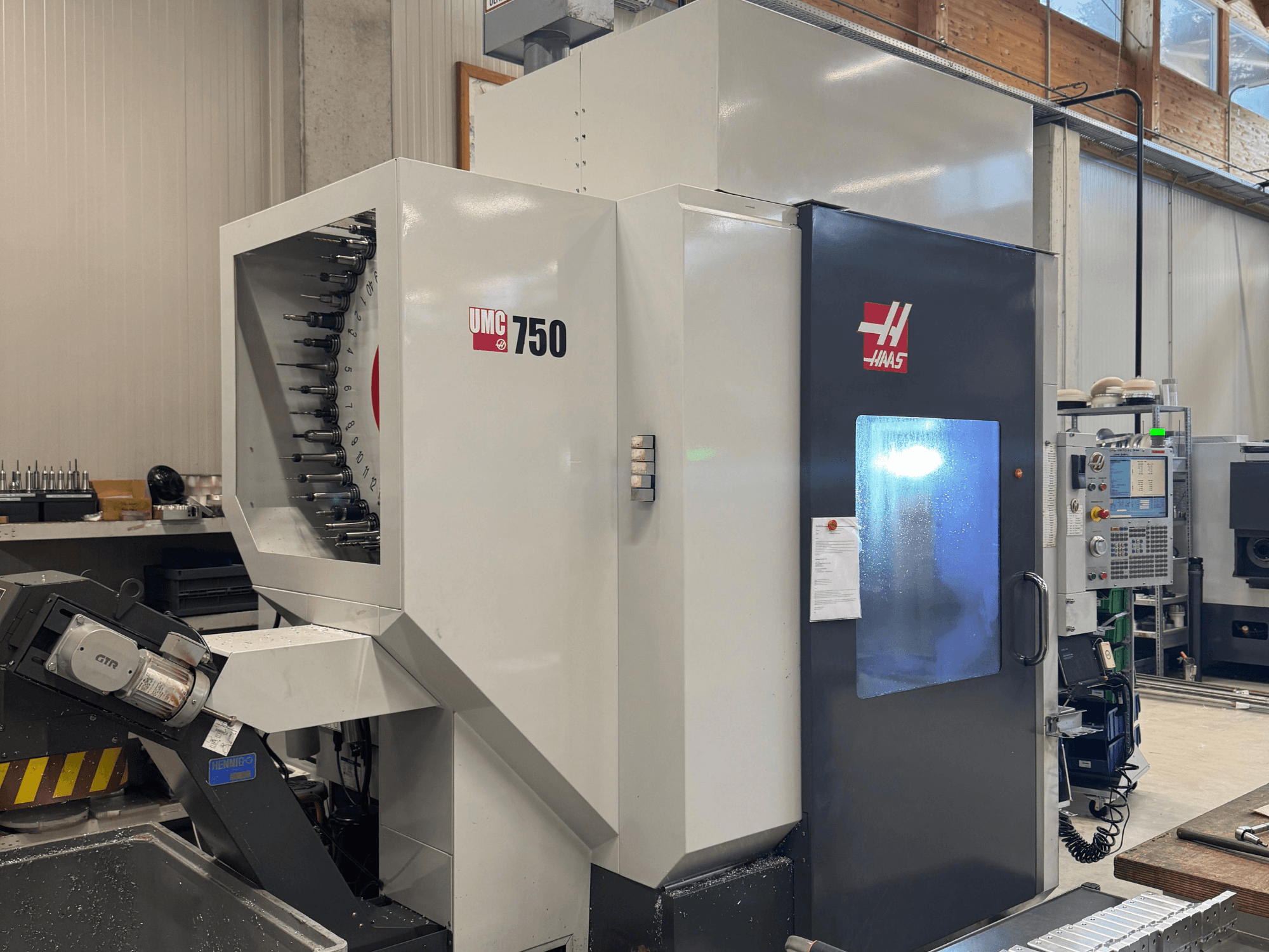 Haas UMC 750 işleme merkezi, önden görünüm, atölye ortamında takım tutucu ve kontrol panelini gösterir.