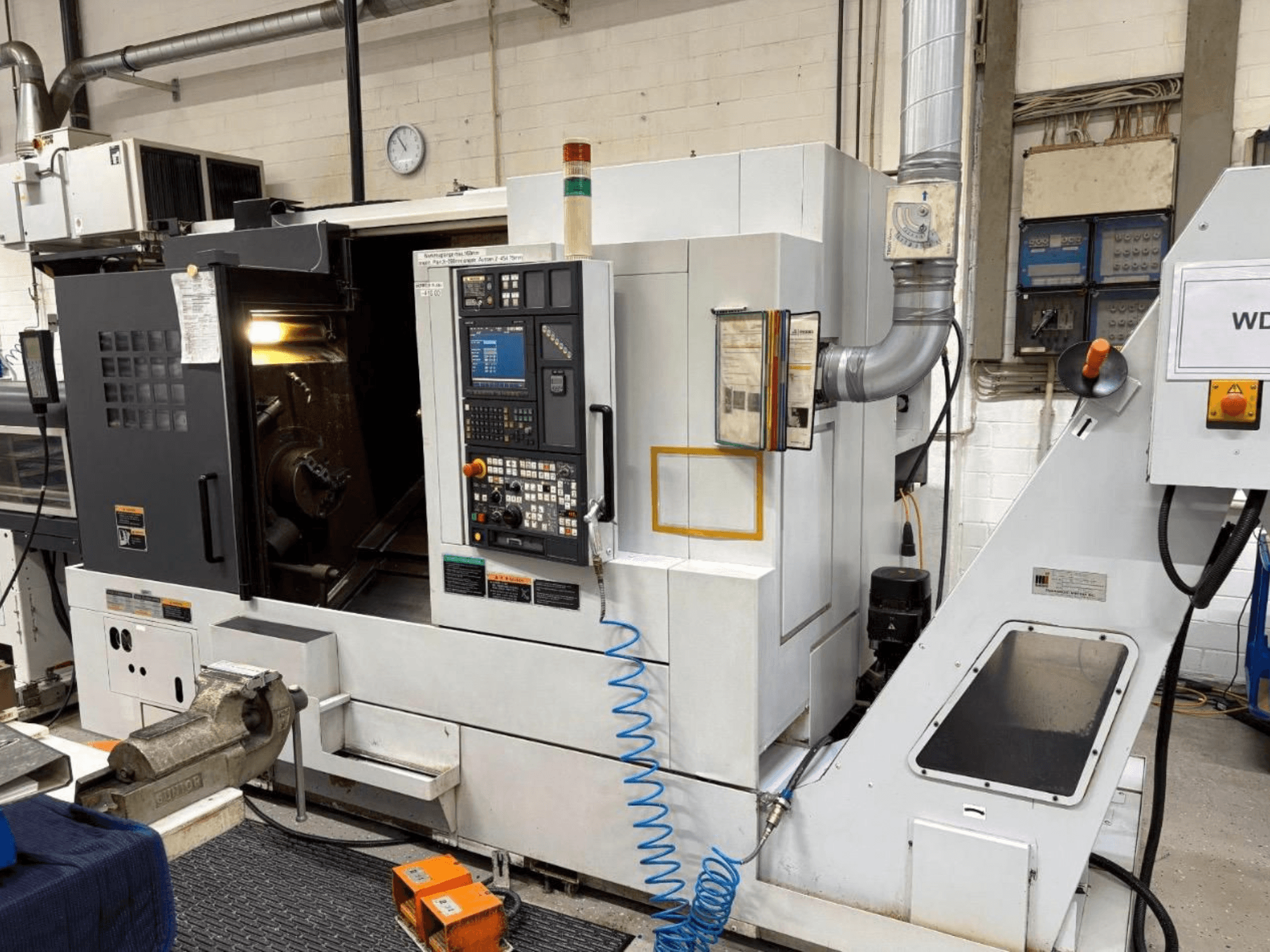 MORI SEIKI NL 2500 SY Torna-Freze Merkezi, önden görünüm, kontrol panelini ve işleme alanını gösterir. Görünür soğutma sistemi ve aksesuarlar.