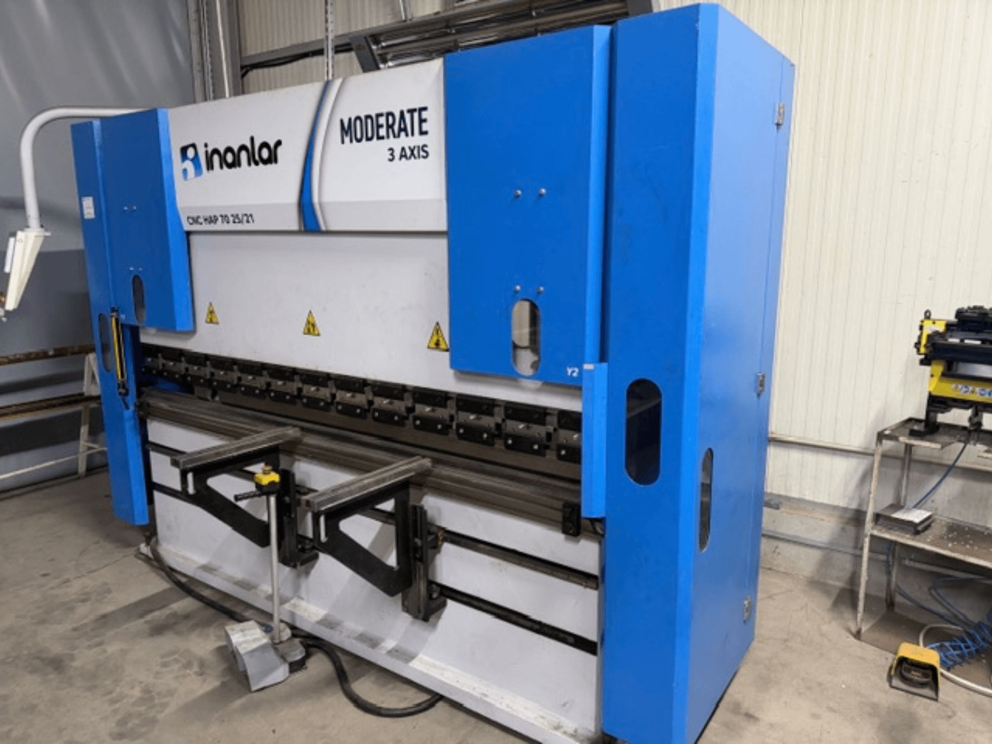 Mavi renkli İnanlar Moderate 3 Eksen CNC makinesi, önden görünüm, gövde üzerinde görünür kontrol kolları ve güvenlik etiketleri bulunur.