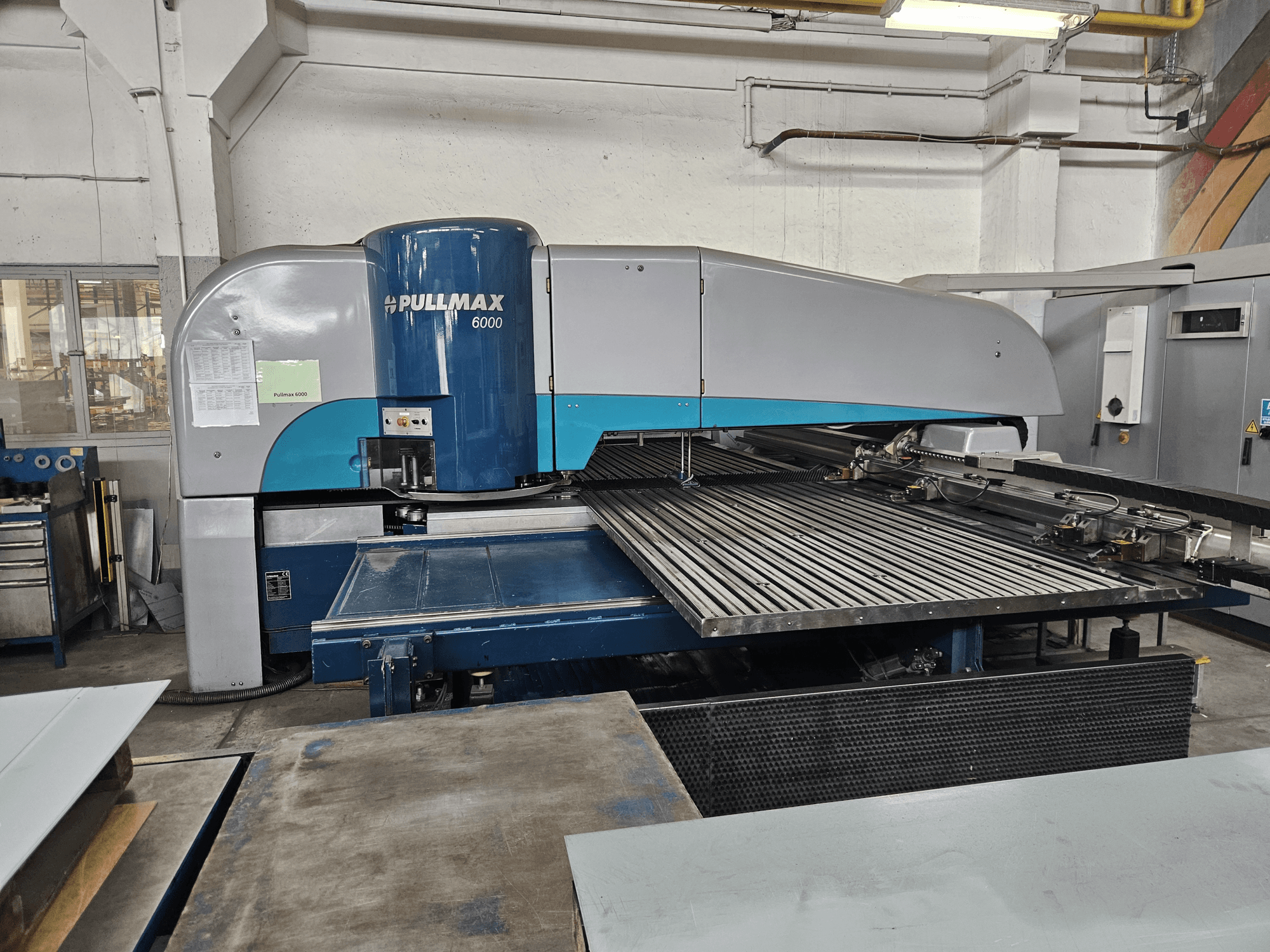 Pullmax 6000 CNC Delme Makinesi'nin önden görünümü, geniş düz yatağını ve metal çerçevesini bir atölye ortamında sergiliyor.