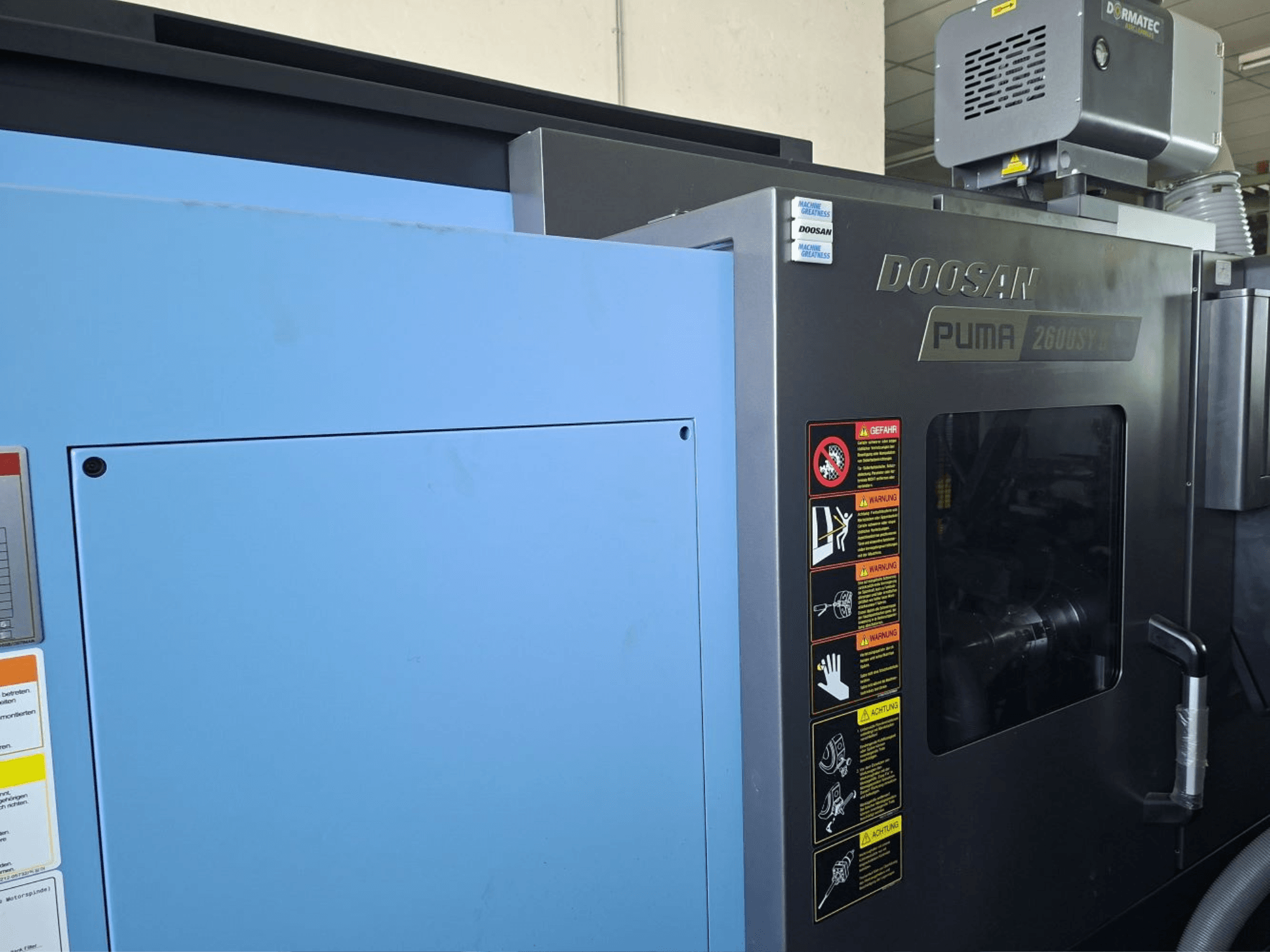 DOOSAN PUMA 2600 SY II yatay tornalama makinesi, önden görünüm, güvenlik etiketleri ve mavi paneller.