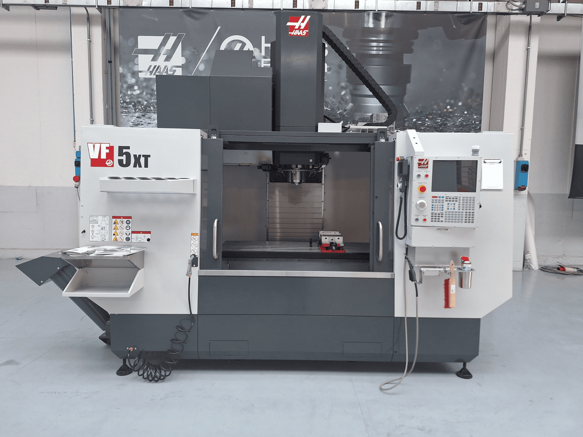 HAAS VF-5/50XT dikey işleme merkezi, önden görünüm; kontrol paneli, iş mili bölgesi ve takım deposu gösterilmektedir.