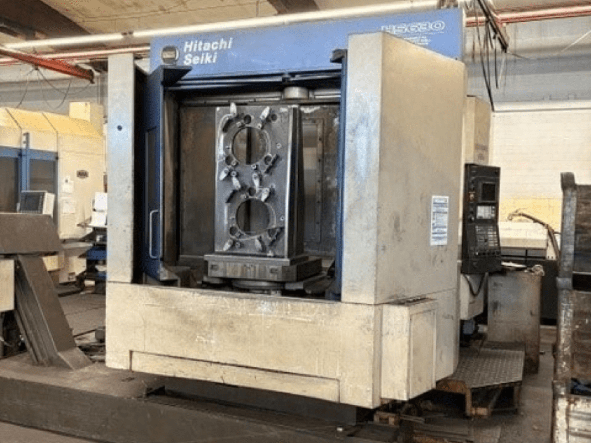 Hitachi Seiki HS630 yatay işleme merkezi; bir iş parçası ve kontrol panelini gösteren önden görünüm.