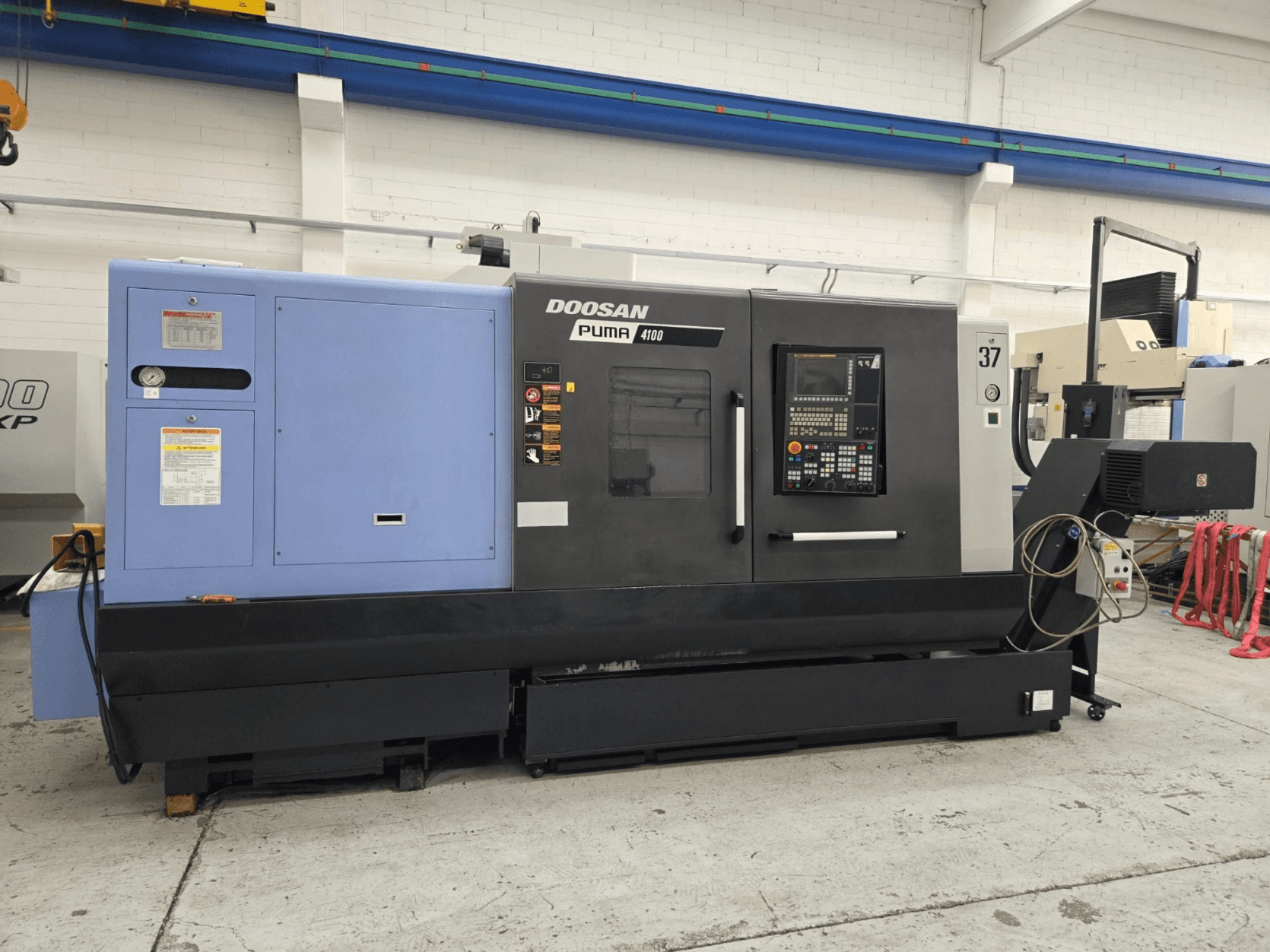Doosan Puma 4100 CNC torna tezgahı, önden görünüm; kontrol paneli, mavi güç ünitesi ve operasyonel rehberlik için ayrıntılı etiketlere sahiptir.
