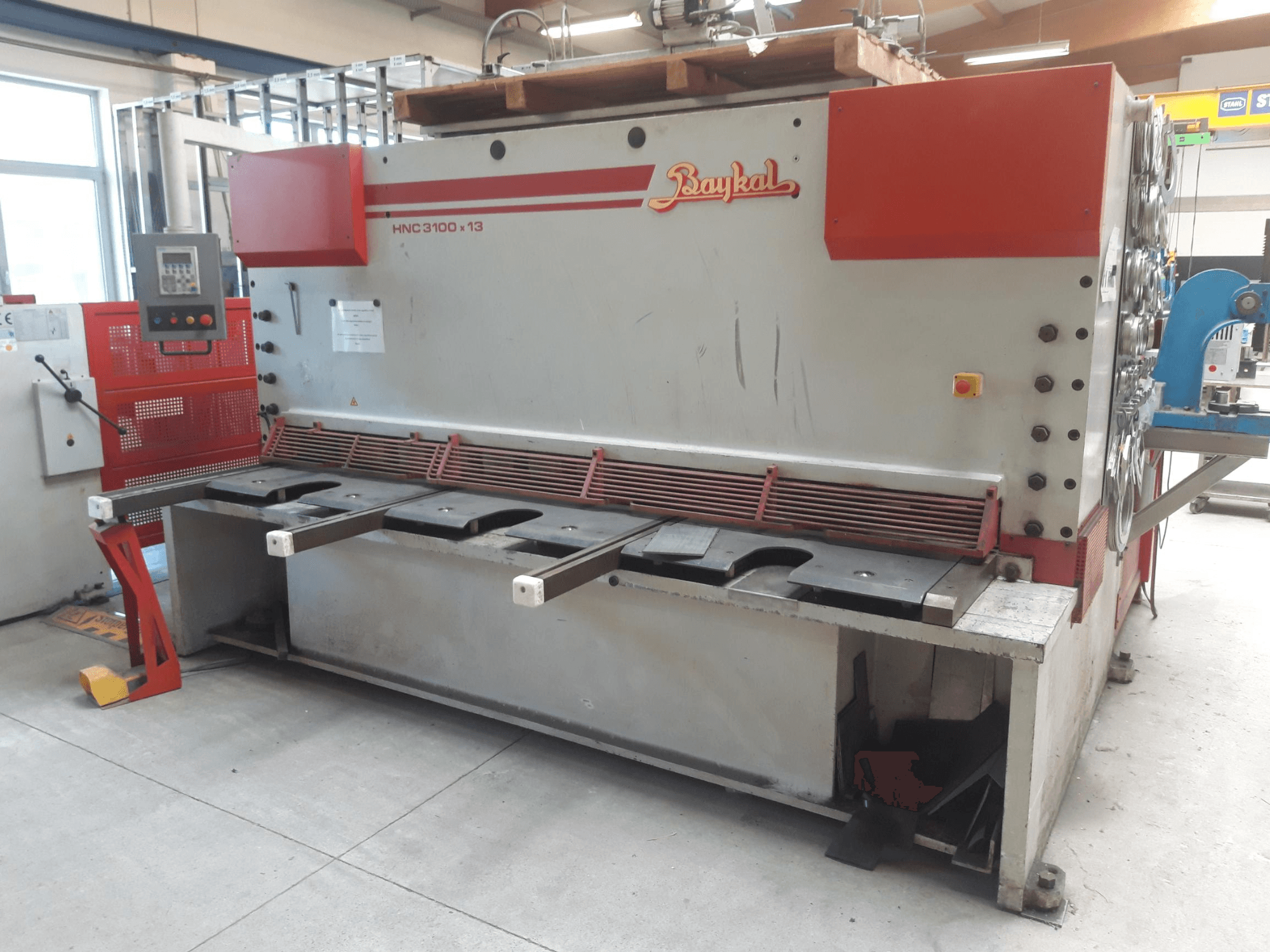 Baykal HNC 3100x13 CNC kesme makinesinin önden görünümü; kontrol paneli, metal kesme alanı ve atık toplama bölmesini içermektedir.