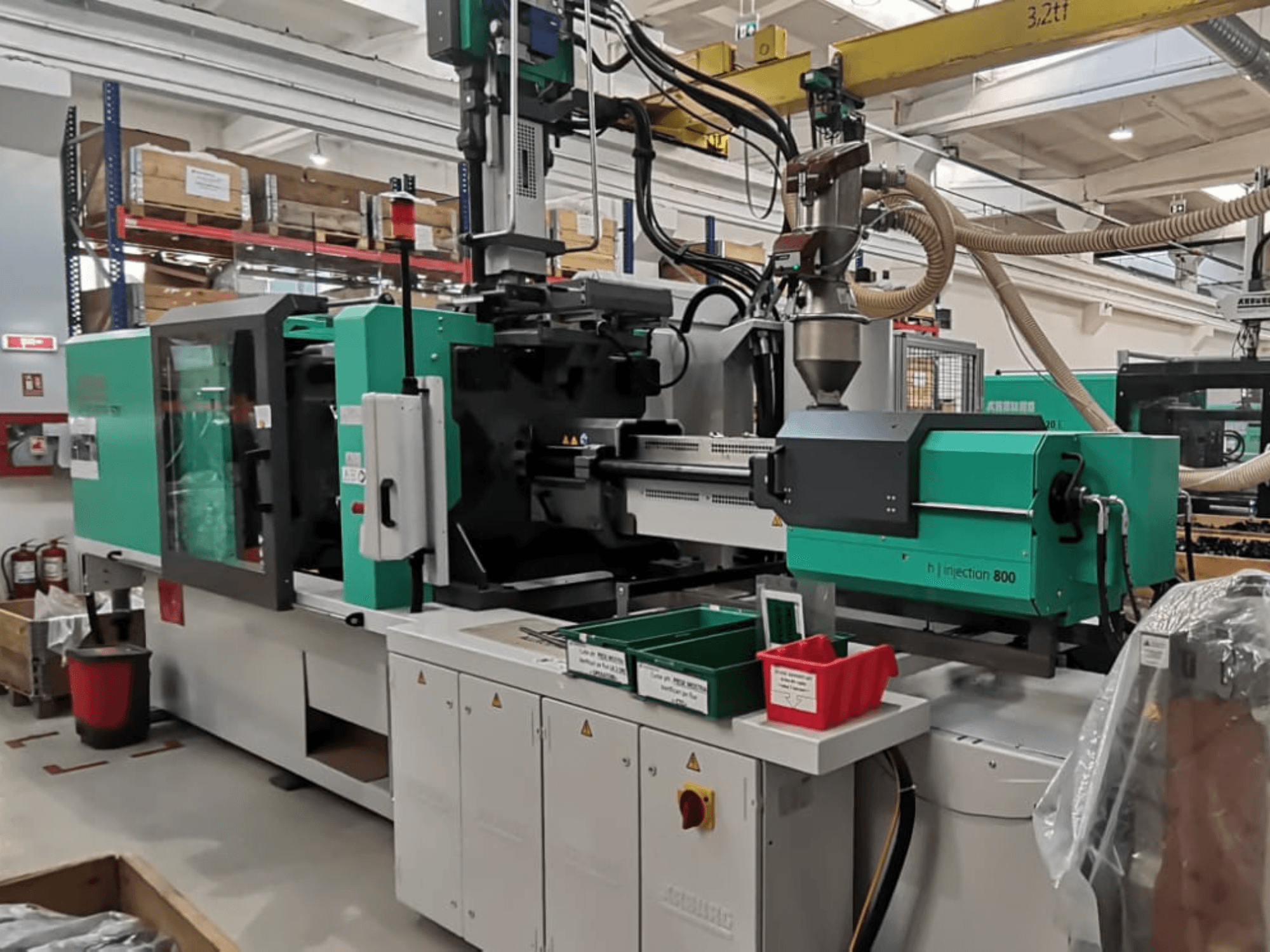 Bir fabrikadaki H enjeksiyon 800 makinesi, önden görünüm, yeşil ve siyah tasarımlı, kontrol panelleri ve parça kutuları ile.