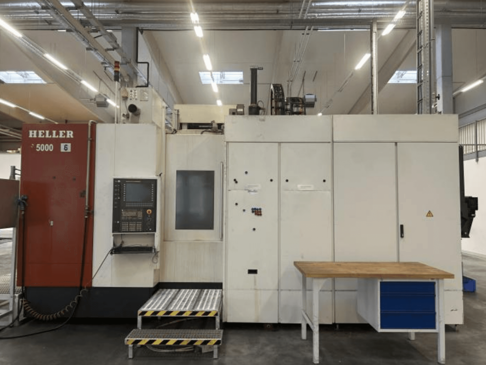 Kontrol paneli, yükseltme platformu ve bitişiğindeki iş masası ile birlikte HELLER H5000 yatay işleme merkezinin önden görünümü.